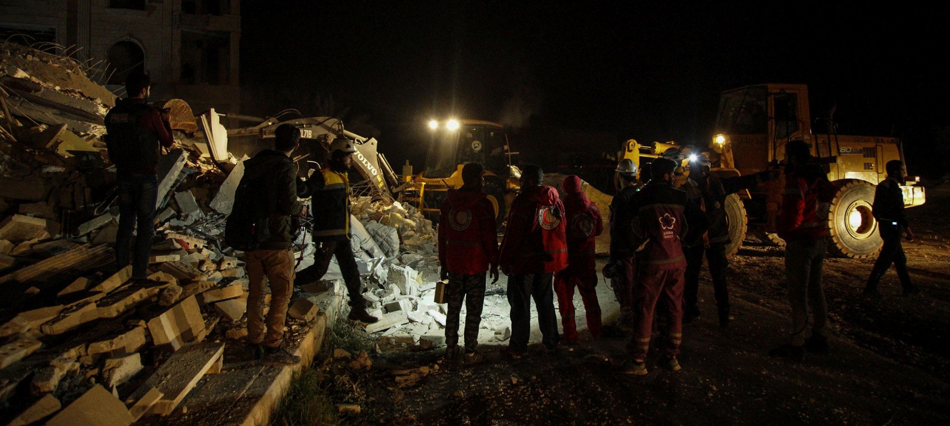 epa06496994 Syrian civil defense volunteers walk next to a bulldozer near civilian buildings which were destroyed in airstrikes in in Idlib City, Syria, 04 February 2018. The number of killed and wounded is unclear. According to activists the airstrikes were conducted by Russian warplanes.