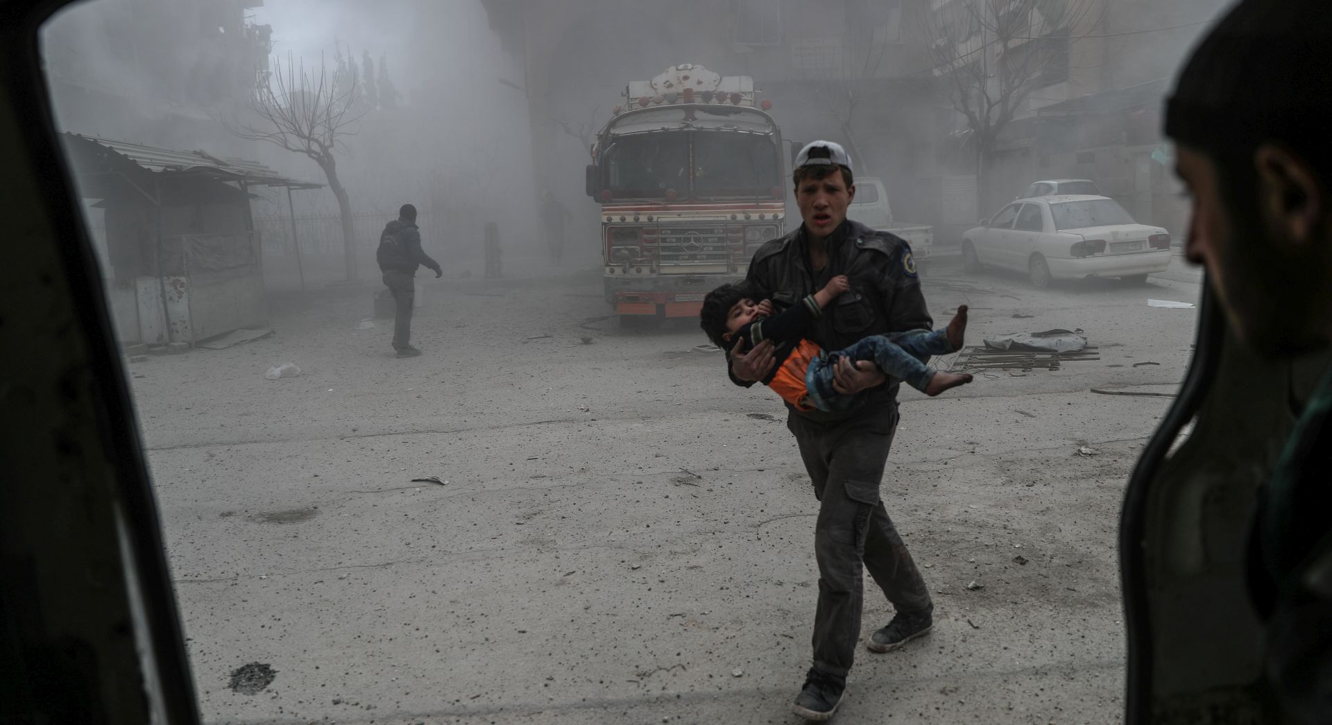 epa06555674 White helmet volunteer carries an injured boy to an ambulance after bombing, in the rebel-held Douma, Eastern Ghouta, Syria, 22 February 2018. More than 42 people got killed in Douma after several airstrikes and shelling by forces allegedly loyal to the Syrian Government. At least 80 people got killed in Eastern Ghouta on the same day, according to local sources.  EPA/MOHAMMED BADRA