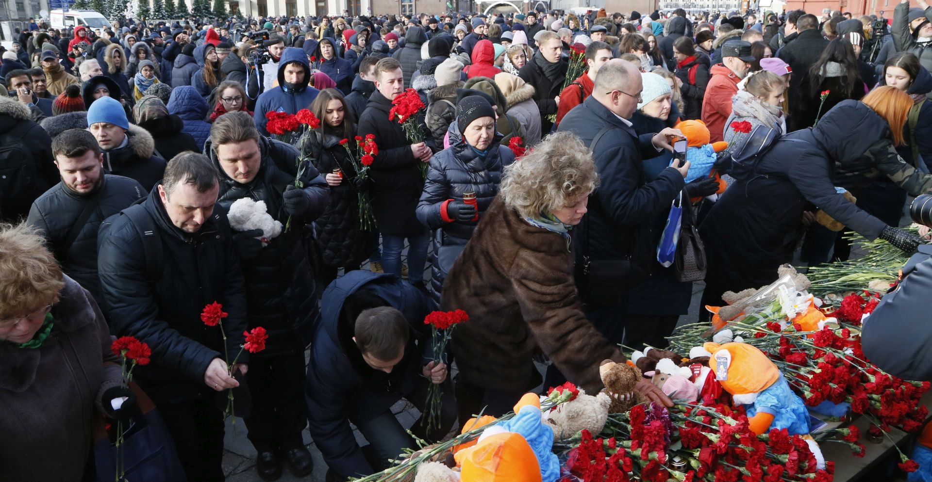 epa06632385 People lay flowers at a makeshift memorial for victims of a fire in the Kemerovo's Zimnyaya Vishnya shopping center at the Manezhnaya square  near the Kremlim in Moscow, Russia, 27 March 2018. Latest media reports that 64 people died in the fire, including many children.Russian President Vladimir Putin signed a decree declaring 28 March 2018 a day of mourning in Russia for the victims of Kemerovo tragedy.  EPA/MAXIM SHIPENKOV