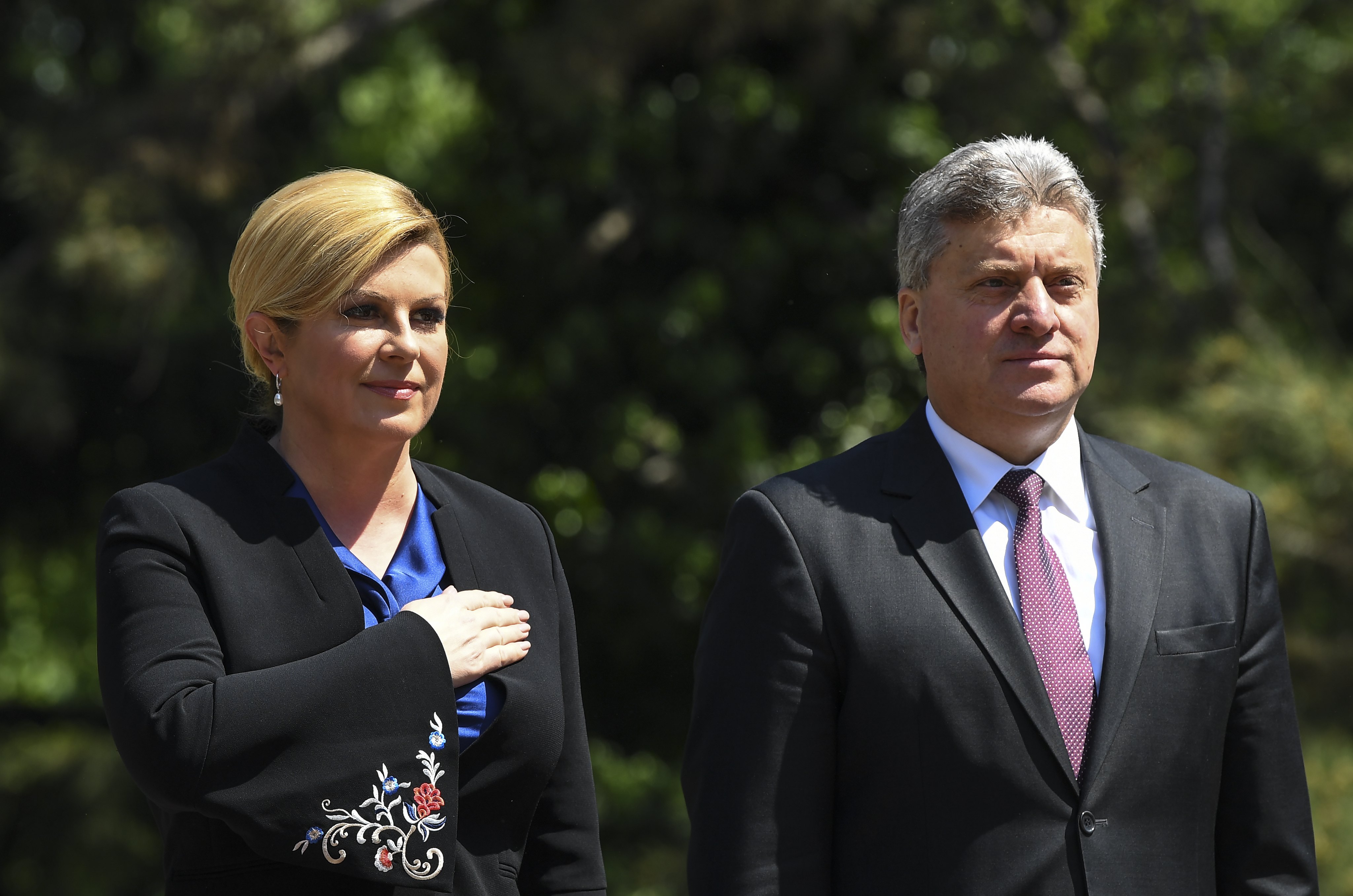 epa06693816 Macedonian President George Ivanov (R) and his Croatian counterpart Kolinda Grabar-Kitarovic (L) listen to the national anthems during a welcome ceremony in Skopje, The Former Yugoslav Republic of Macedonia, 26 April 2018. The Croatian President arrived for a two-day official visit to Macedonia.  EPA/GEORGI LICOVSKI
