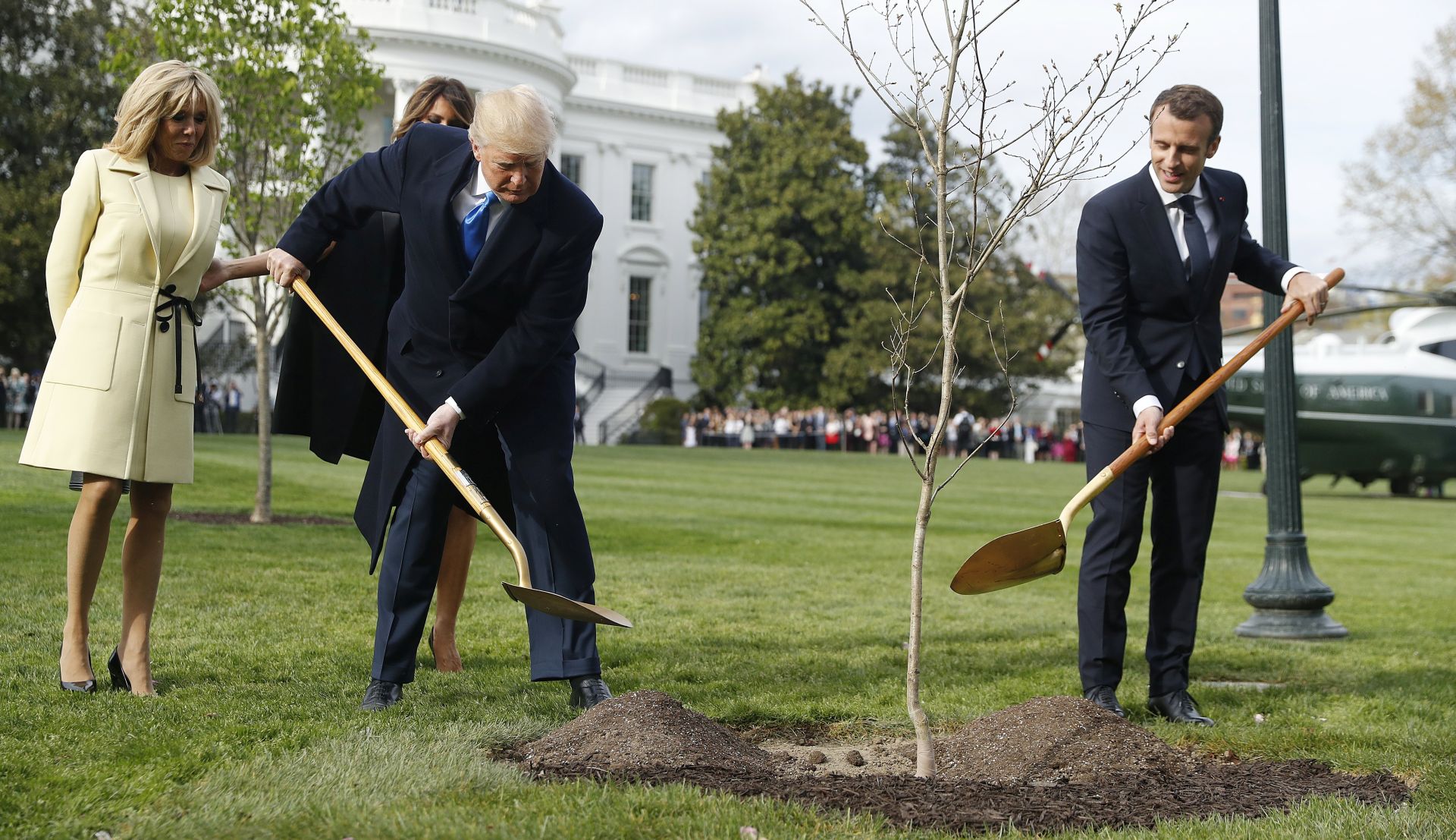 epa06688013 US President Donald J. Trump (L) and First Lady Melania Trump (obscured) with French President Emmanuel Macron (R) and his wife Brigitte Macron (L) as they participate in a tree planting in front of the White House in Washington, DC, USA, 23 April 2018. President Macron will be in DC for three days for a state visit at the White House and an address to a joint session of Congress on 25 April.  EPA/SHAWN THEW