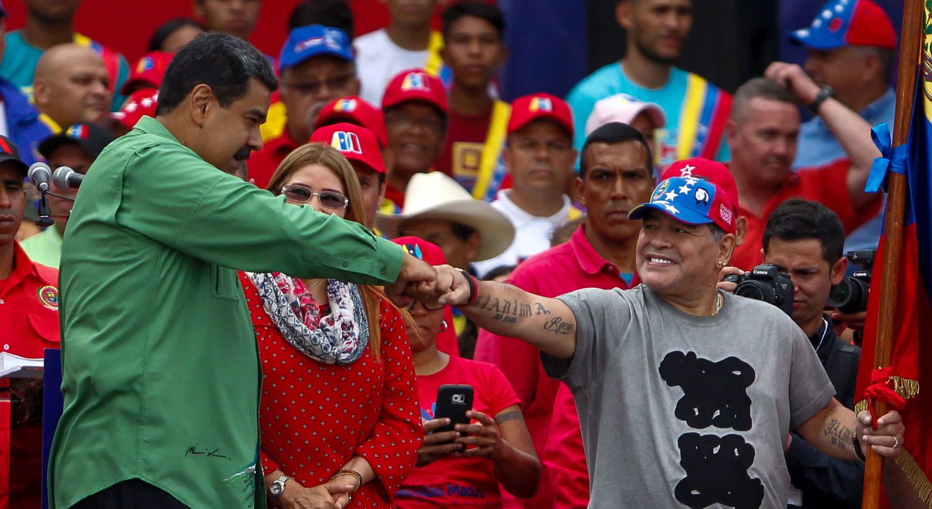 epa06745848 Venezuelan President Nicolas Maduro (L) accompanied by the First Lady Cilia Flores (C) fist bumps Argentine former soccer player Diego Maradona (R) during the close of campaign in Caracas, Venezuela, on 17 May 2018. Maduro close his campaign with the promise to solve the economic crisis of the country. The presidential election is set for 20 May.  EPA/Cristian Hernandez