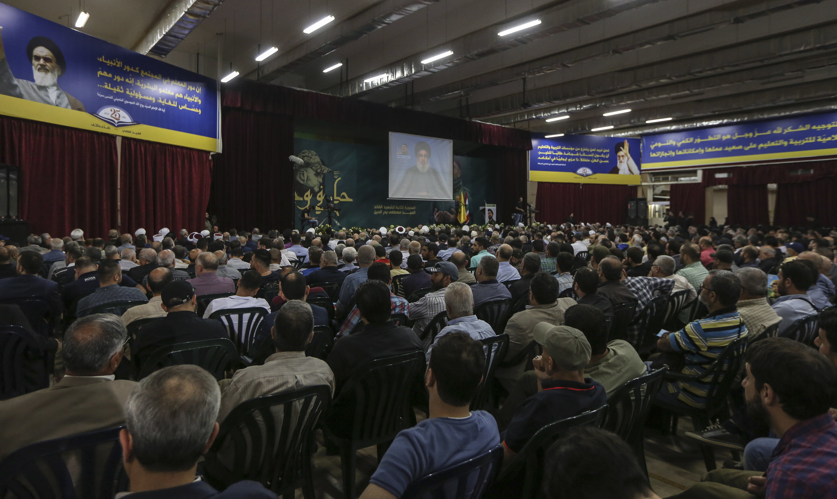 epa06736659 Supporters of Hezbollah watch Secretary General of Hezbollah Hassan Nasrallah on a big screen as he delivers his speech from an undisclosed location, during the celebration of the Second anniversary of the assassination of Hezbollah Jihadist Leader  'Sayed Mustafa Amin Badr Al-Din', in the southern suburb of Beirut, Lebanon, 14 May 2018. Badr al-Din, who was considered Hezbollah's most senior military commander, was killed in an attack in Syria in 2016. Nasrallah spoke about the situations in Palestine, Lebanon, Syria, and other Arab countries.  EPA/NABIL MOUNZER