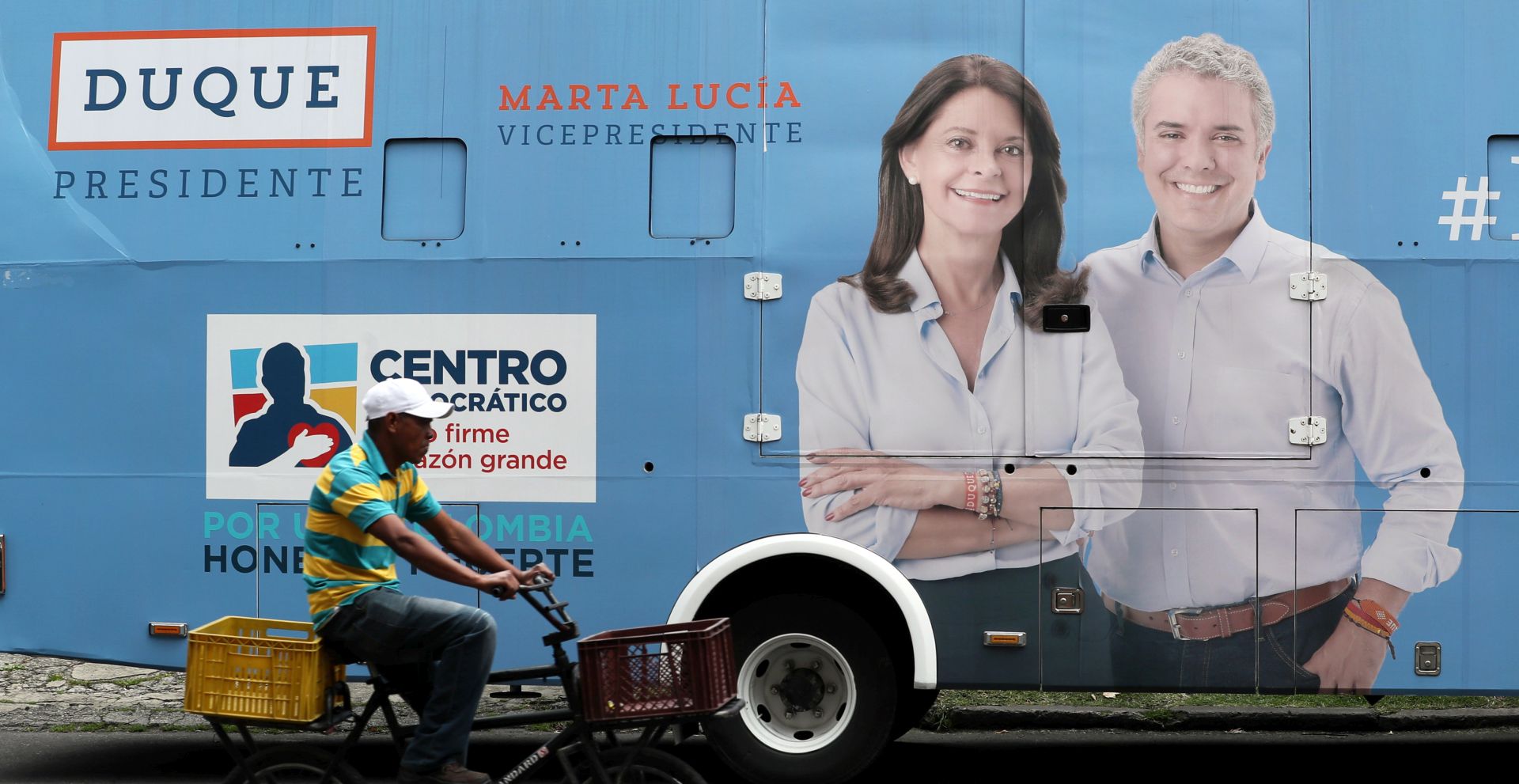 epa06808515 A man passes in front of a bus with advertising of the presidential candidate of Colombia Ivan Duque (R) and his candidate to the vice-presidency Marta Lucia Ramirez, in Bogota, Colombia, 14 June 2018. The second electoral round of the Colombian presidential elections will be held on 17 June, in which the candidate of the Democratic Center party Ivan Duque and the leftist of the Colombia Human movement, Gustavo Petro will face each other.  EPA/MAURICIO DUENAS CASTANEDA