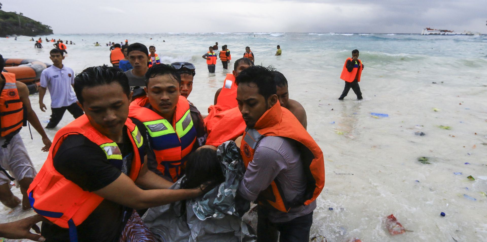 epa06860813 Indonesian rescuers evacuate a victim of a sinking ferry (far right) off the coast of Selayar island, in South Sulawesi, Indonesia, 03 July 2018. At least 12 people were killed as a ferry with 139 passengers on board sank off the coast of Selayar island.  EPA/MUSTAFA SYAHRIL