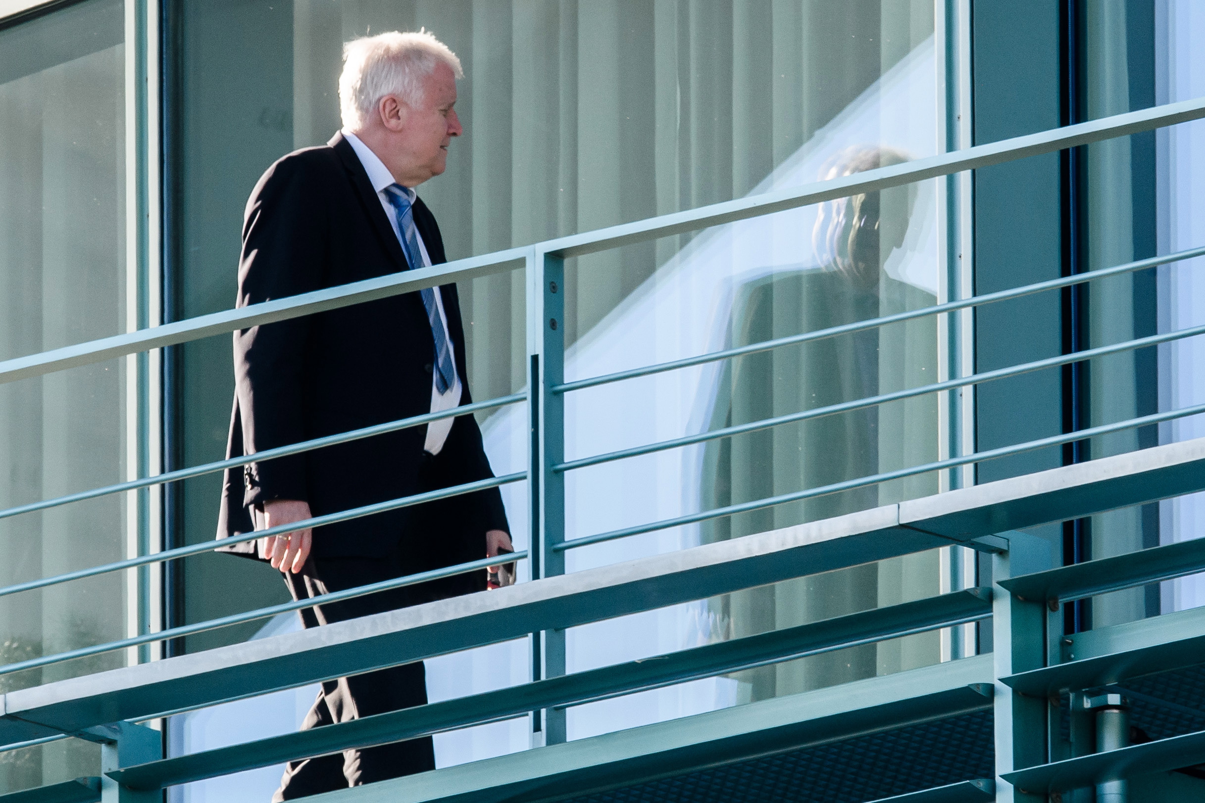 epa06861705 German Minister of Interior, Construction and Homeland and chairman of the German Christian Social Union (CSU) Horst Seehofer walks on a balcony during the beginning of a coalition summit at the Chancellery in Berlin, Germany, 03 July 2018. Leading politicians of the government coalition of the Christian Democrats (CDU), the Christian Social Union (CSU) and the Social Democratic Party (SPD) meet in Berlin to discuss the results of a recent government crisis. The CDU and its sister party CSU were engaged in a heated debate over Europe's future course in refugee policy causing a severe government crisis.  EPA/CLEMENS BILAN