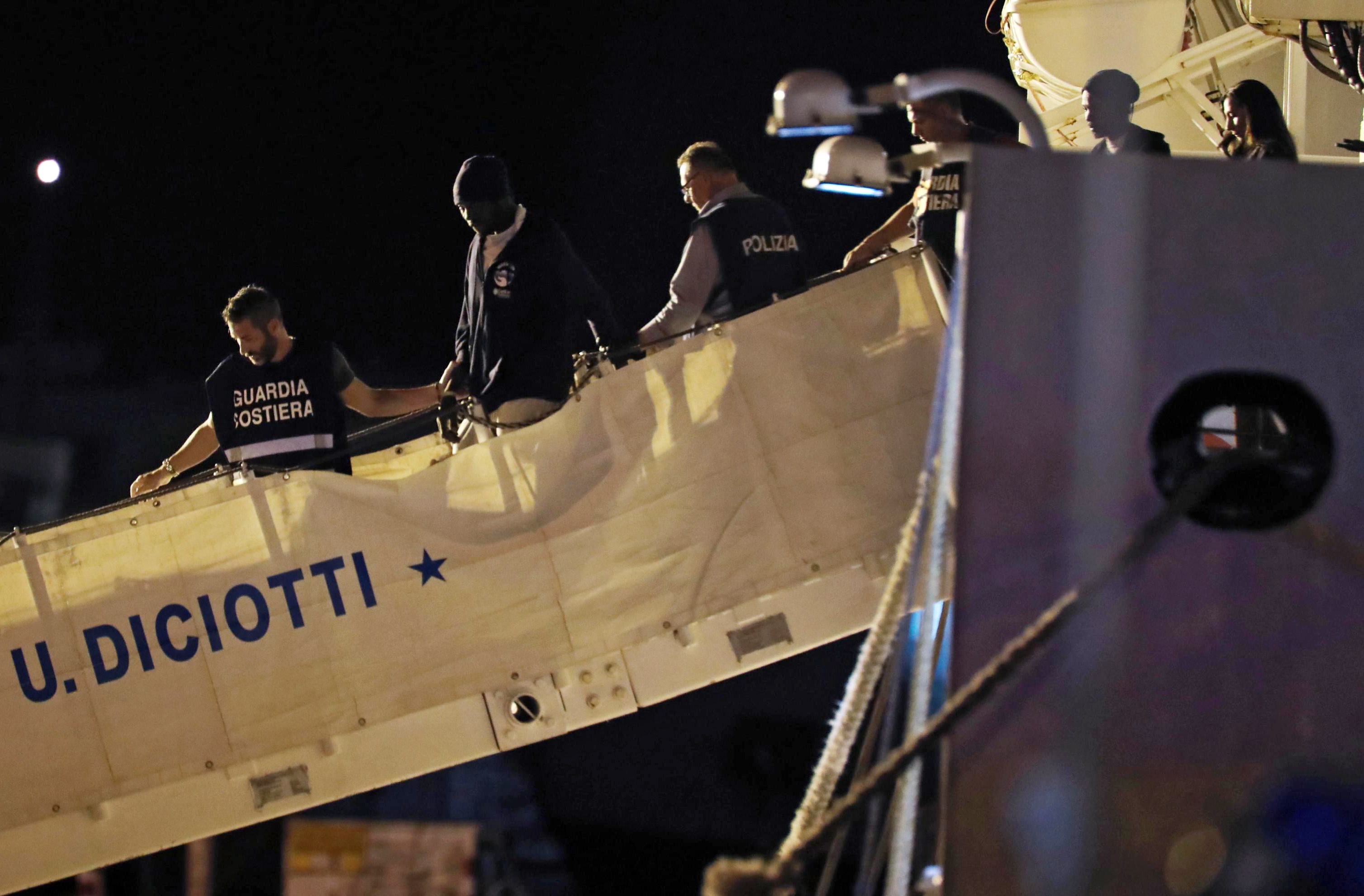 epa06885000 Italian Coast Guard escort migrants off the Coast Guard's ship 'Diciotti' that carried 67 migrants who were taken in from 'Vos Thalassa' in the Mediterranenan, as it is docked at the port of Trapani, Italy, 12 July 2018 (issued 13 July 2018). Italian Interior Minister Salvini said on 12 July he would not authorise any migrants to get off coast guard ship Diciotti, but Prime Minister Conte overruled and allowed the entrance.  EPA/Igor Petyx