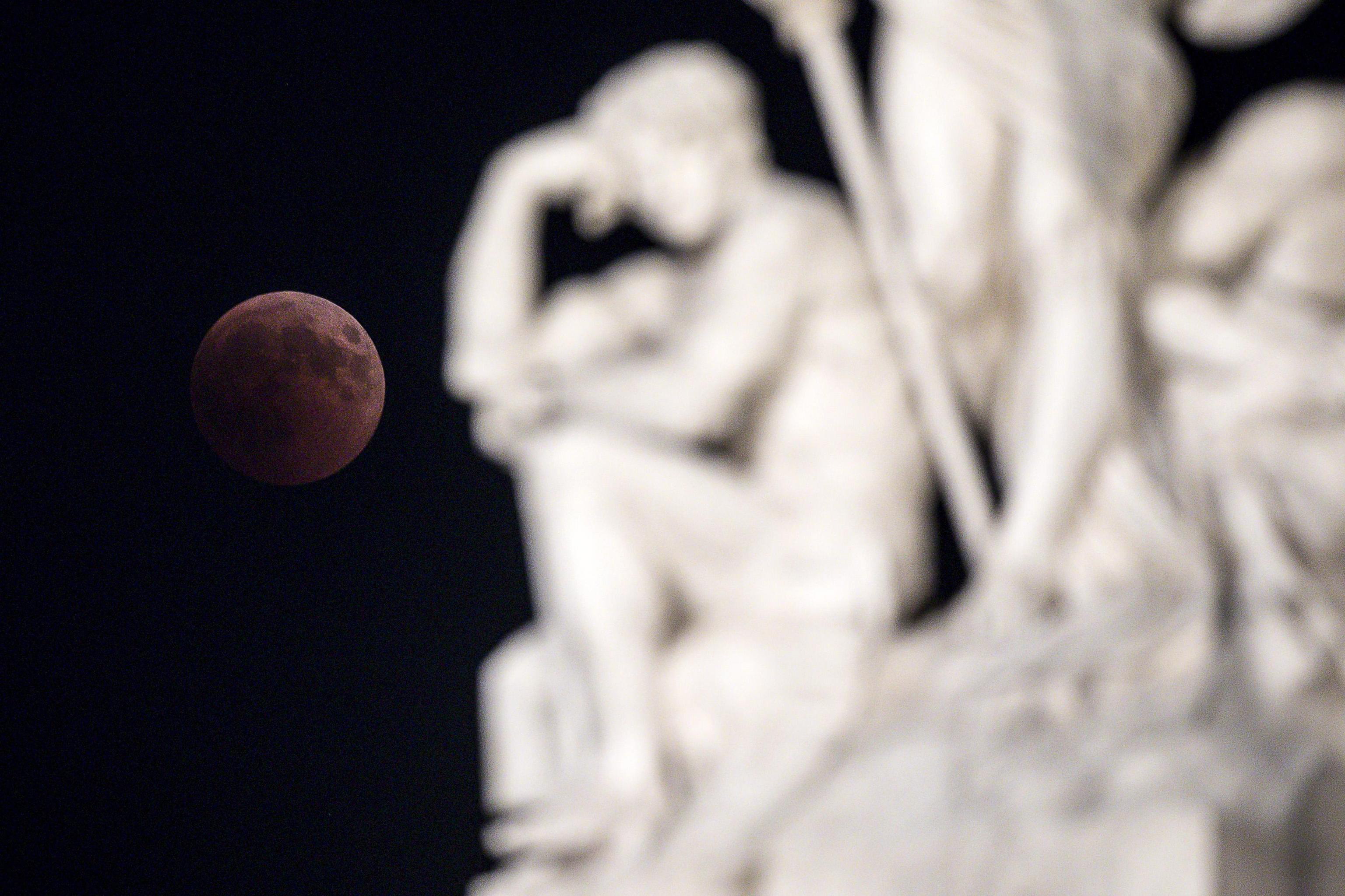 epa06914857 The moon turns red during a total lunar eclipse, over a statue of Vittoriano, Venezia square, in Rome, Italy, 27 July 2018. The second total lunar eclipse of 2018 will be visible in large parts of Australia, Asia, Africa, Europe, and South America. The totality will last for 103 minutes, making it the longest lunar eclipse of the 21st century.  EPA/ANGELO CARCONI
