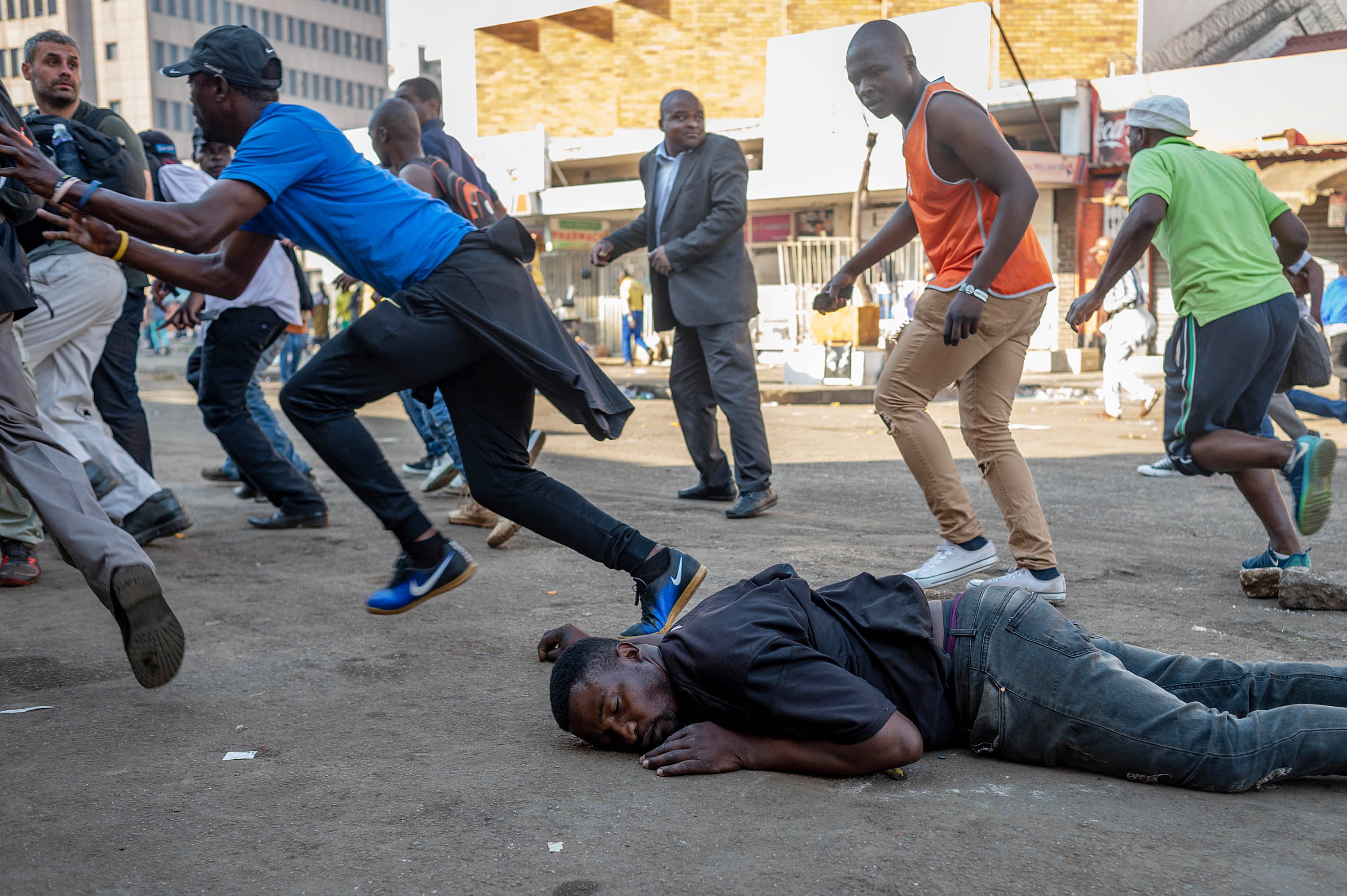 epa06922015 A man who was shot in the back by a live round fired by the Zimbabwean Army lies on the ground bleeding during a protest against the vote count in Harare, Zimbabwe, 01 August 2018. The Zimbabwean army refused to allow journalists to treat the man and attempted to arrest them.  EPA/YESHIEL PANCHIA