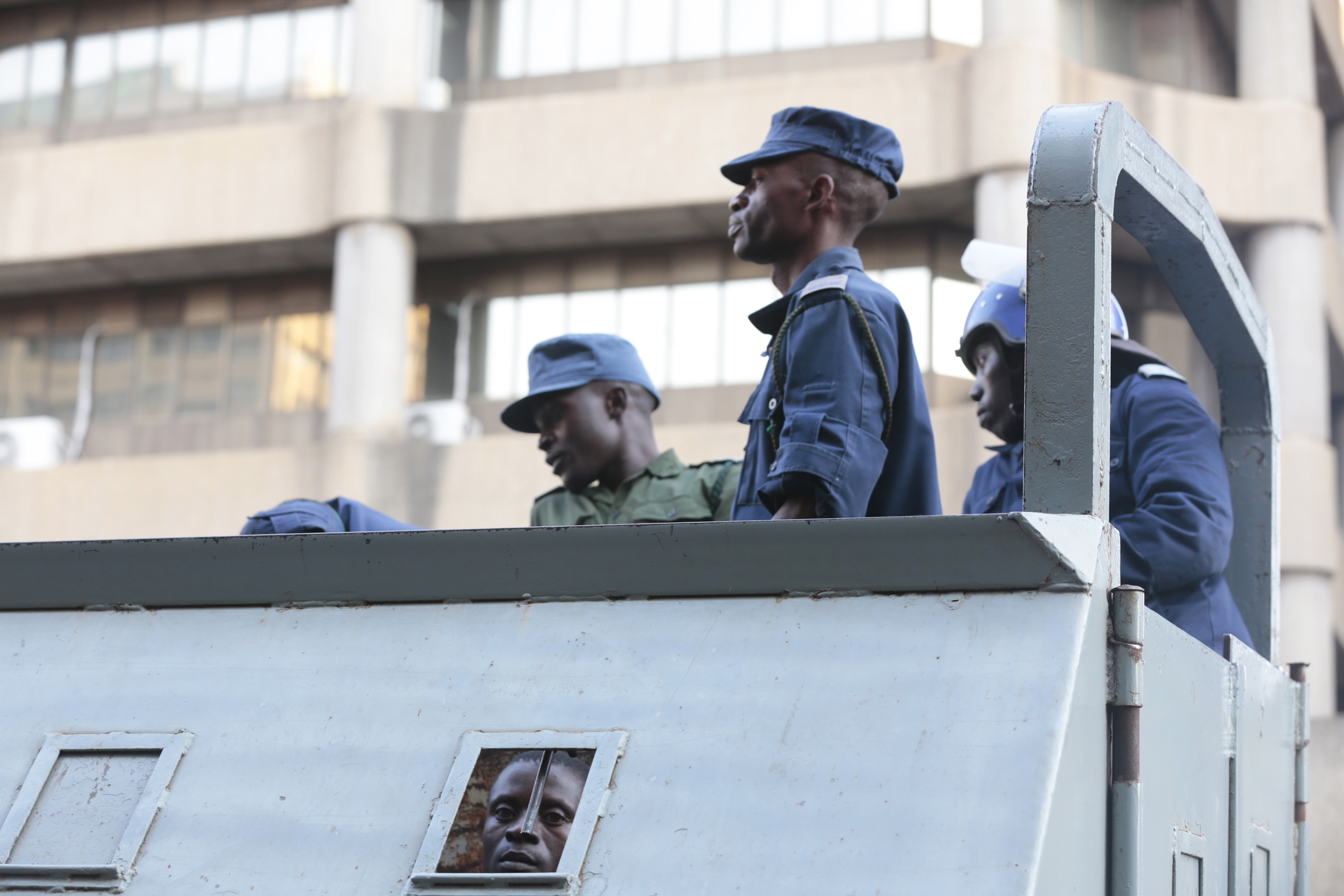 epa06924025 One of the 16 Movement For Democratic Change (MDC) Alliance members, who have been arrested by the Zimbabwe Republic Police (ZRP) at the party's headquarters looks through a small window of a police truck in Harare, Zimbabwe, 02 August 2018. The Police raid followed a violent response by the Zimbabwean army to opposition protests and clashes on 01 August, in which six people have been killed, according to reports.  EPA/AARON UFUMELI