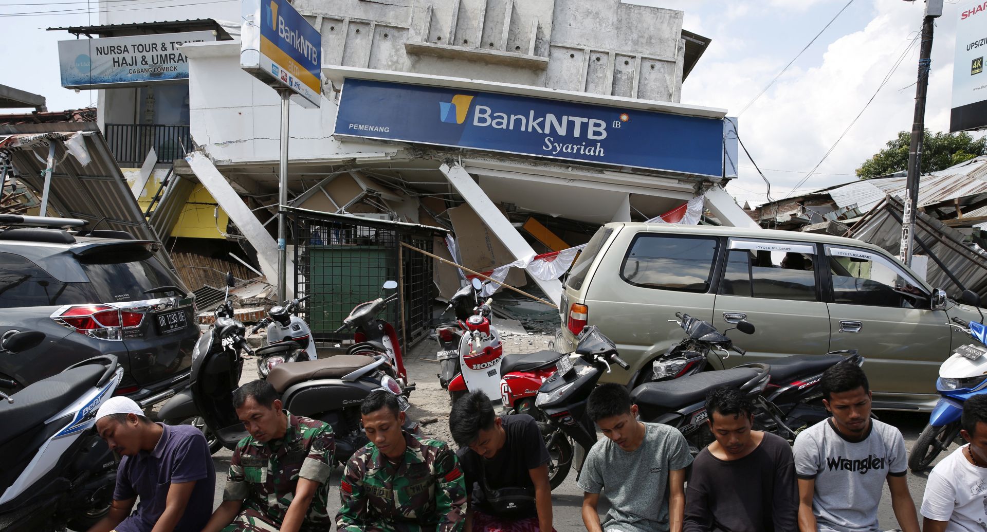 epa06939847 Residents pray in front of a collapsed building  during Friday prayer at a village in Bangsal, northern Lombok, West Nusa Tenggara, Indonesia, 10 August 2018. According to media reports, a 7.0 magnitude quake hit Indonesia's island of Lombok on 05 August, killing at least 159 people. Additional media reports state that on 09 August 2018, Lombok was hit by a strong tremor which the United States Geological Survey (USGS) said had a magnitude of 5.9, and caused structural damage.  EPA/ADI WEDA