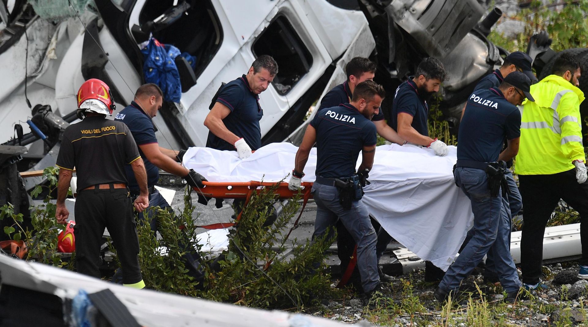 epa06949718 Rescuers recover a victim after a highway bridge collapsed in Genoa, Italy, 14 August 2018. At least 22 people are believed to have died as a large section of the Morandi viaduct upon which the A10 motorway runs collapsed in Genoa on Tuesday. Both sides of the highway fell. Around 10 vehicles are involved in the collapse, rescue sources said. The viaduct gave way amid torrential rain.  EPA/LUCA ZENNARO