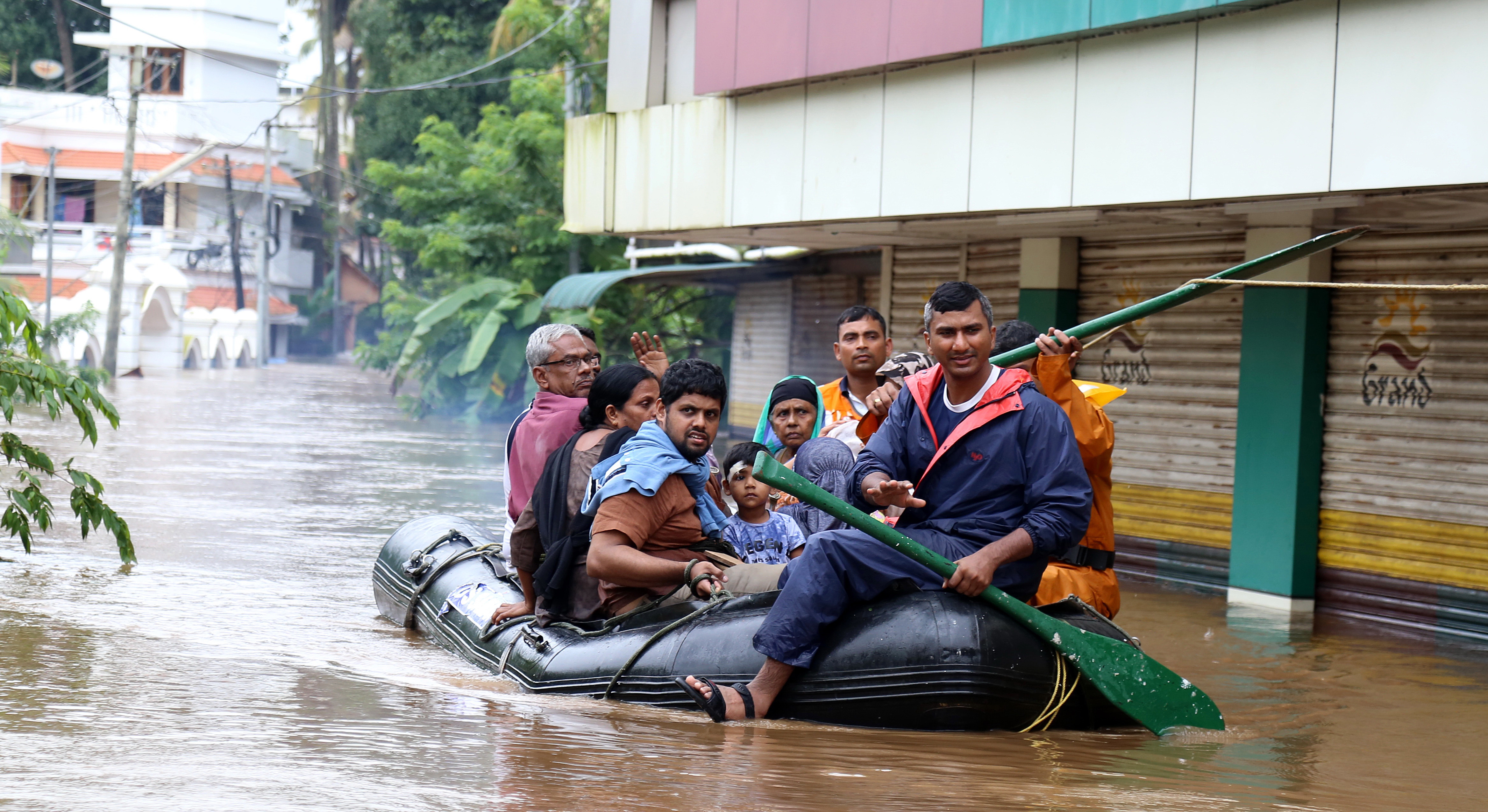 epa06952637 Indian people use an inflatable boat to reach a safer place in the flooded water in Kochi, Kerala state, India, 16 August 2018. According to reports, the region is on a high alert with schools and offices been closed due to the rising water levels of Periyar river after the gates of the Idukki reservoir were opened. The Indian state of Kerala has been hit by heavy rains that caused floods and reportedly killed at least 65 people.  EPA/PRAKASH ELAMAKKARA