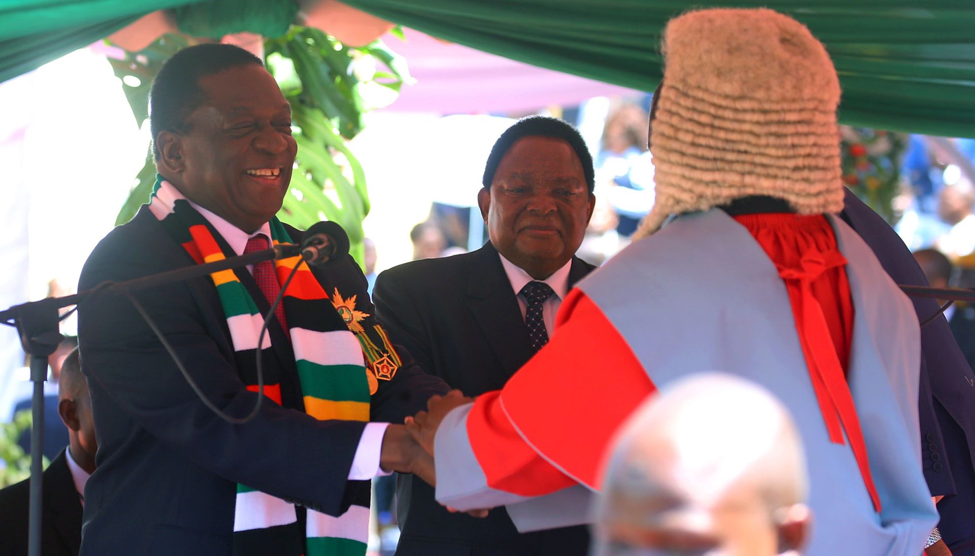 epa06973538 Emmerson Mnangagwa (L) shakes hands with Zimbabwe's Chief Justice Luke Malaba (R) after being sworn in as the second executive President of Zimbabwe at the National Sports Stadium in Harare, Zimbabwe, 26 August 2018. Mnangagwa was declared the winner of the just ended harmonised elections by the the Constitutional Court on 24 August 2018. Others are not identified.  EPA/AARON UFUMELI