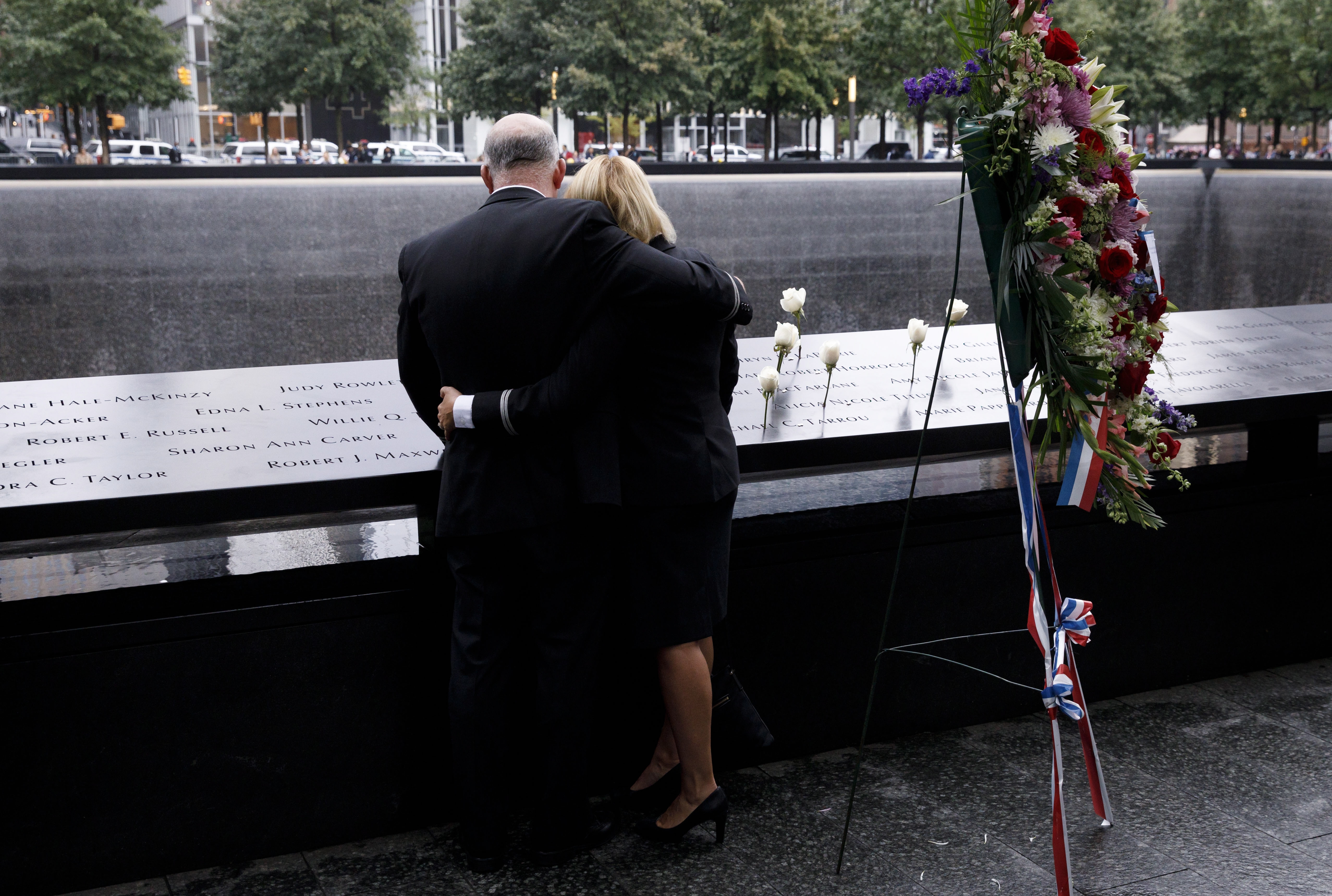 epa07012627 People embrace at South pool of the 9/11 Memorial during ceremonies marking the 17th anniversary of terrorist attacks in New York, New York, USA, 11 September 2018.  EPA/JUSTIN LANE