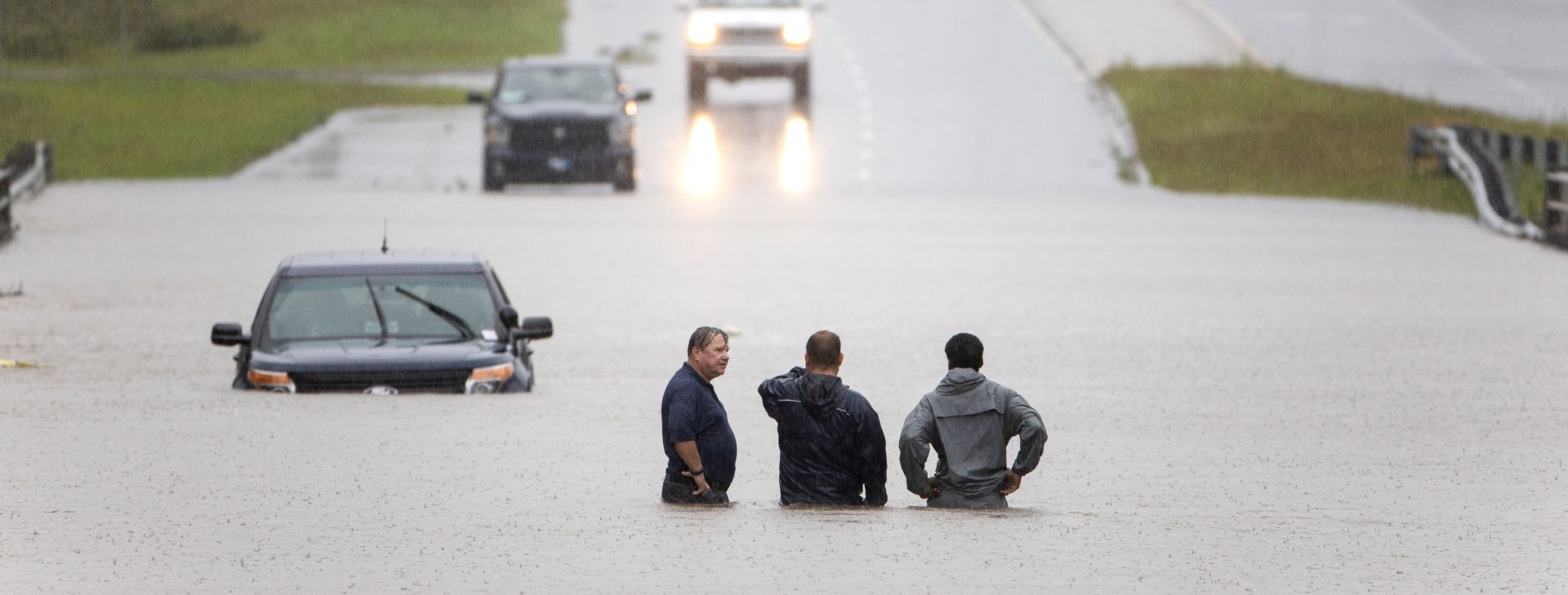 epa07023442 Bystanders help a stranded motorist after floodwaters from Hurricane Florence flooded his car along Route 17 near Holly Ridge, North Carolina USA, 15 September 2018. Storm surge and heavy flooding from the hurricane has inundated much of Eastern North Carolina. Florence has been downgraded to a tropical storm but is still expected to bring a storm surge with heavy flooding to the Carolinas.  EPA/JIM LO SCALZO