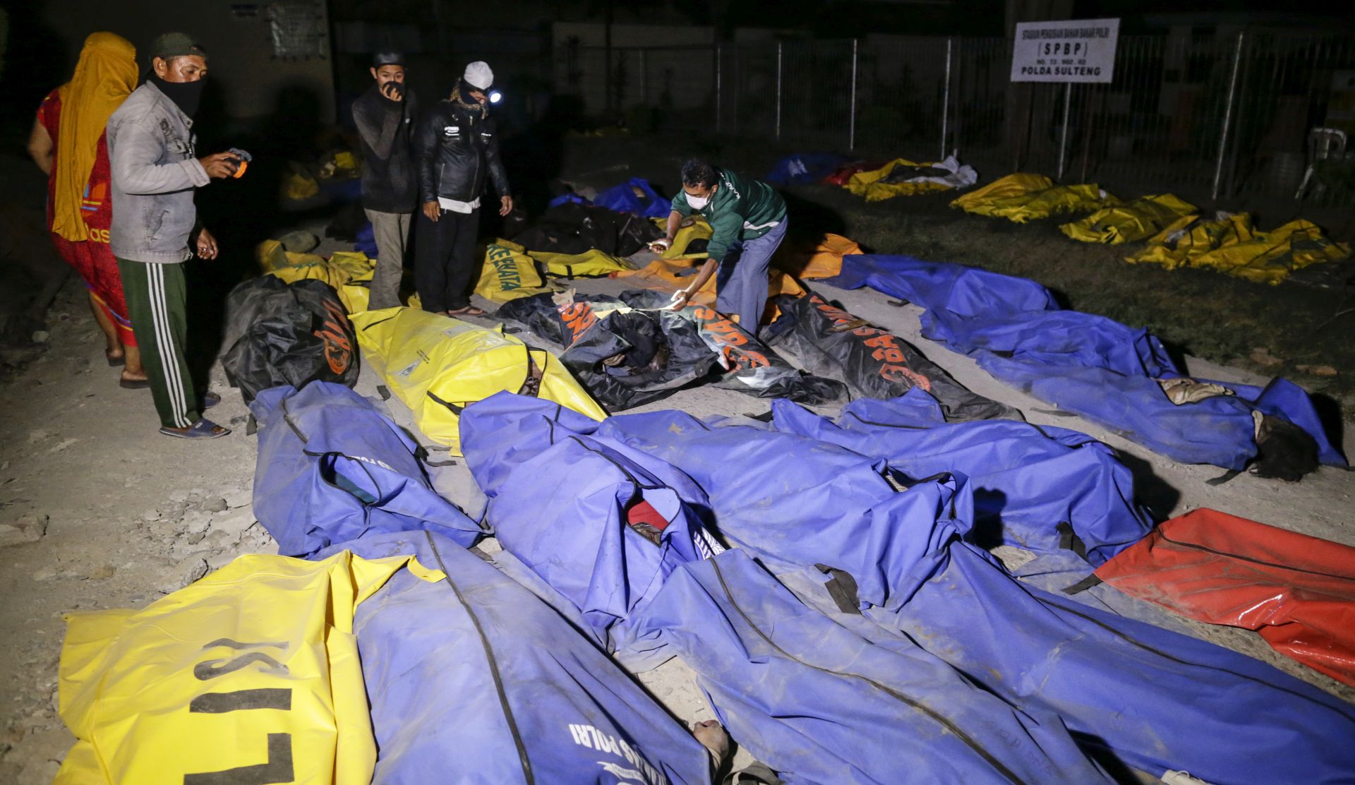 epa07056351 Indonesian men check the body of earthquake and tsunami victims as they look for their relatives at a police hospital in Palu, central Sulawesi, Indonesia, 29 September 2018. According to reports, at least 384 people have died as a result of a series of powerful earthquakes that hit central Sulawesi and triggered a tsunami.  EPA/MAST IRHAM