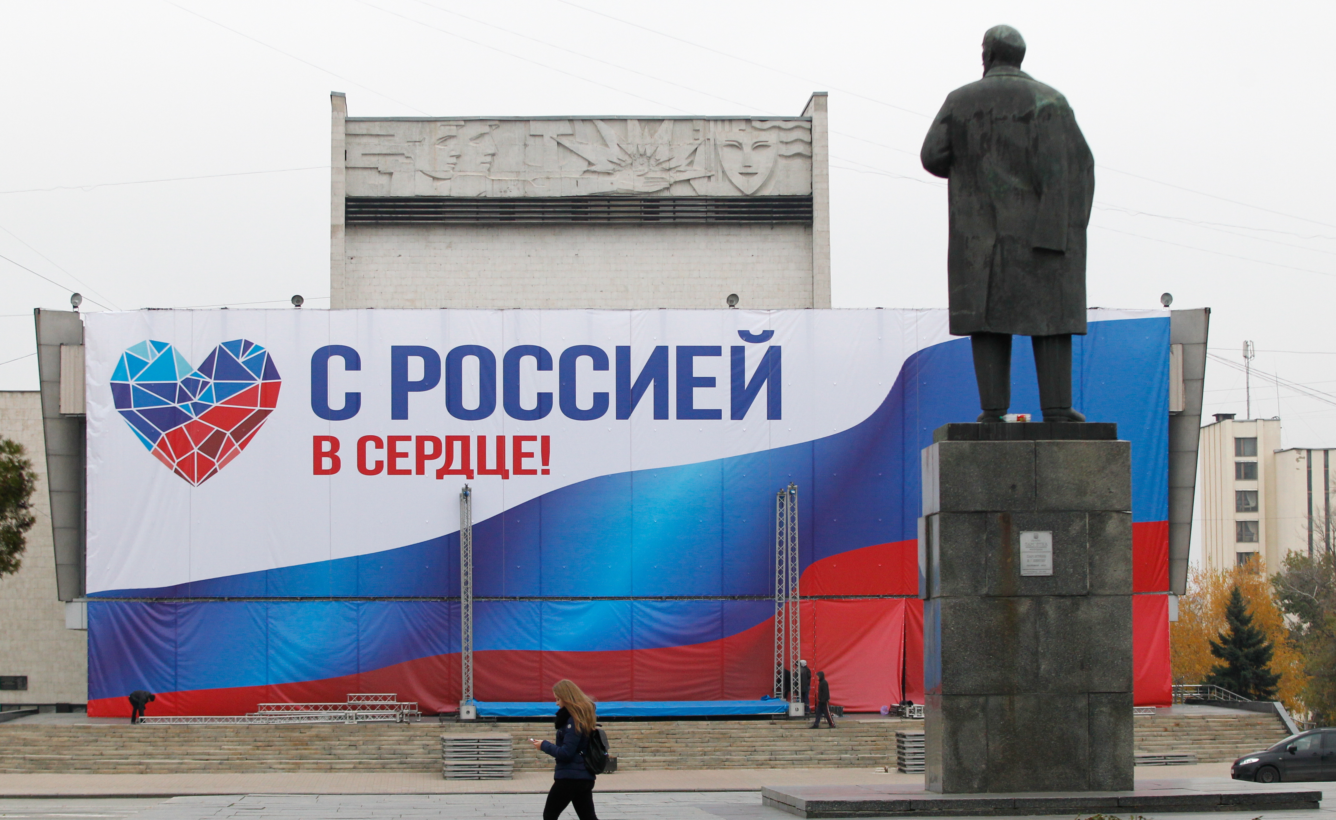 epa07154211 Local residents walk past a banner reading 'With Russia in a heart!' and a monument to the Soviet Union's founder Vladimir Lenin in the pro-Russian rebels controlled city of Luhansk, Ukraine, 09 November 2018. Local citizens of the so-called Donetsk and Luhansk People's Republics (DPR/LPR) prepare to elect their leaders during elections scheduled for 11 November 2018.  EPA/ALEXANDER ERMOCHENKO