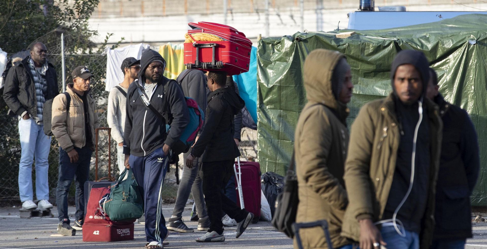 epa07162369 People carry their belongings as authorities clear the migrants camp run by volunteers providing food and shelter to migrants near to Rome's Tiburtina railway station, Rome, Italy, 13 November 2018. Around 200 migrants were in the Baobab Experience camp before the eviction.  EPA/MASSIMO PERCOSSI