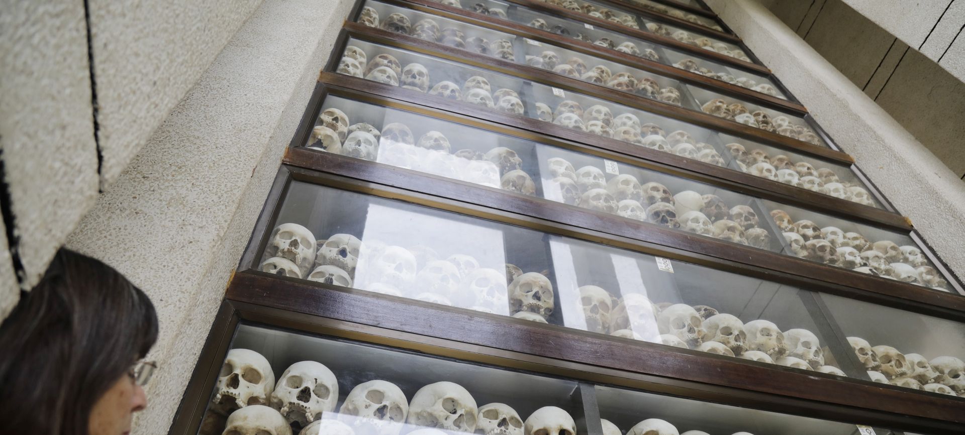 epa07166301 A tourist looks at the remains of victims who died during the Khmer Rouge regime at the Choeung Ek Genocidal Center, on the outskirts of Phnom Penh, Cambodia, 15 November 2018. The Trial Chamber of the Extraordinary Chambers in the Courts of Cambodia (ECCC) will pronounce the judgement in Case 002/02 against former Khmer Rouge leaders Khieu Samphan and Nuon Chea on 16 November 2018, both are charged with crimes against humanity.  EPA/MAK REMISSA