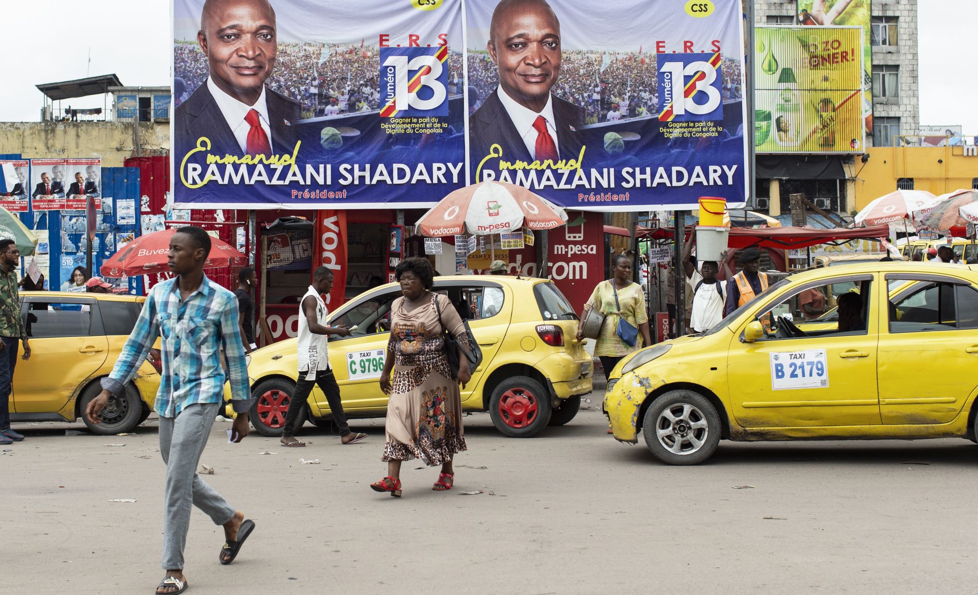 epa07239826 People walk in front of campaign banners of the ruling party candidate Emmanuel Ramazani Shadary in Kinshasa, Democratic Republic of the Congo, 19 December 2018. DR Congo will go to the polls on 23 December in presidential and parliamentary elections. Shadary, a loyalist of outgoing president Joseph Kabila, faces challenges posed by Felix Tshisekedi, the leader of the Union for Democracy and Social Progress (UDPS) party, and the joint opposition candidate Martin Fayulu.  EPA/STEFAN KLEINOWITZ