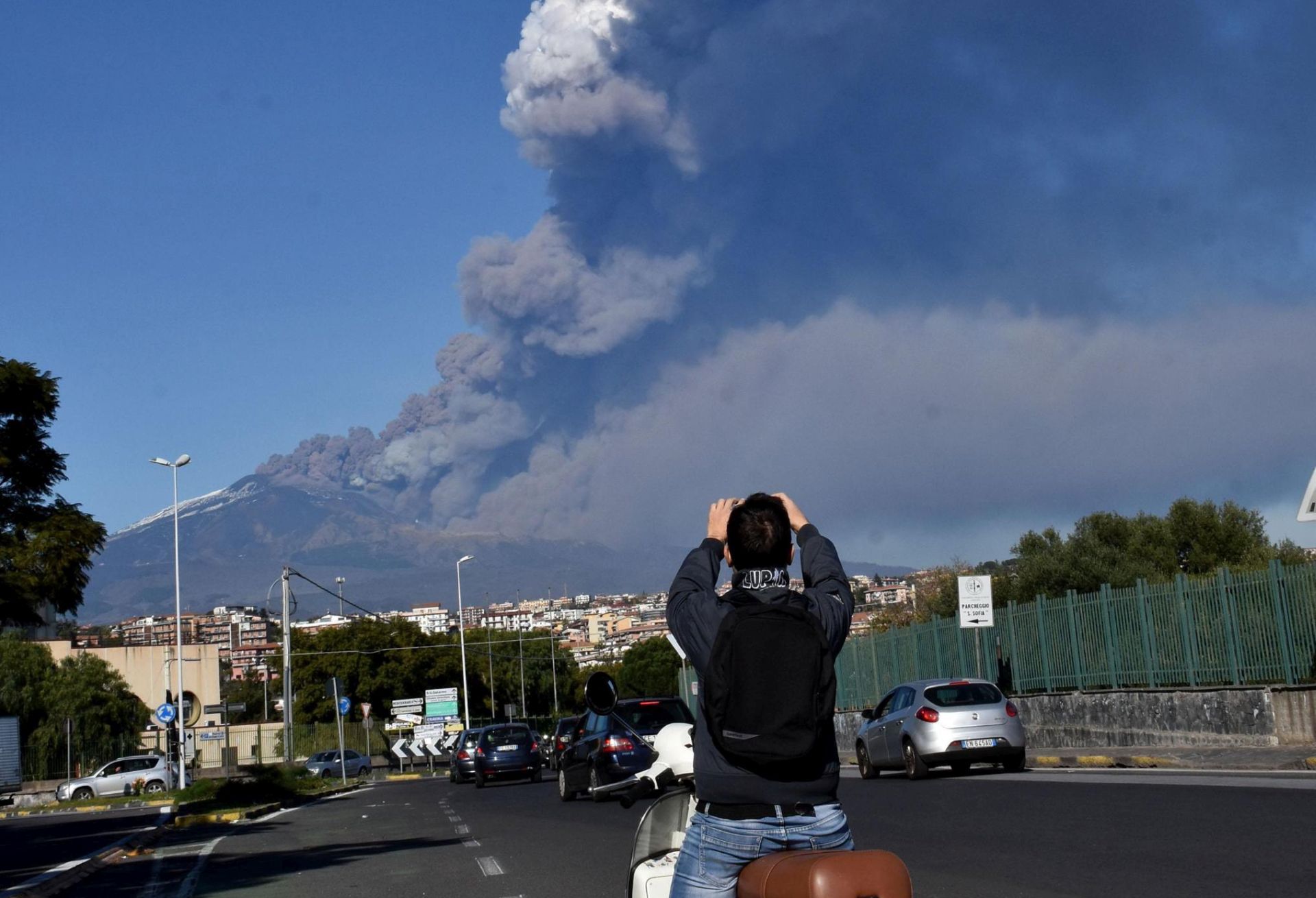 epa07247469 A man takes a photo of a rising plume of smoke coming from Etna volcano in Catania, December 24th 2018. An eruptive fracture opened this morning on Mount Etna at the base of the southeast crater, where explosive activity continues.  EPA/ORIETTA SCARDINO