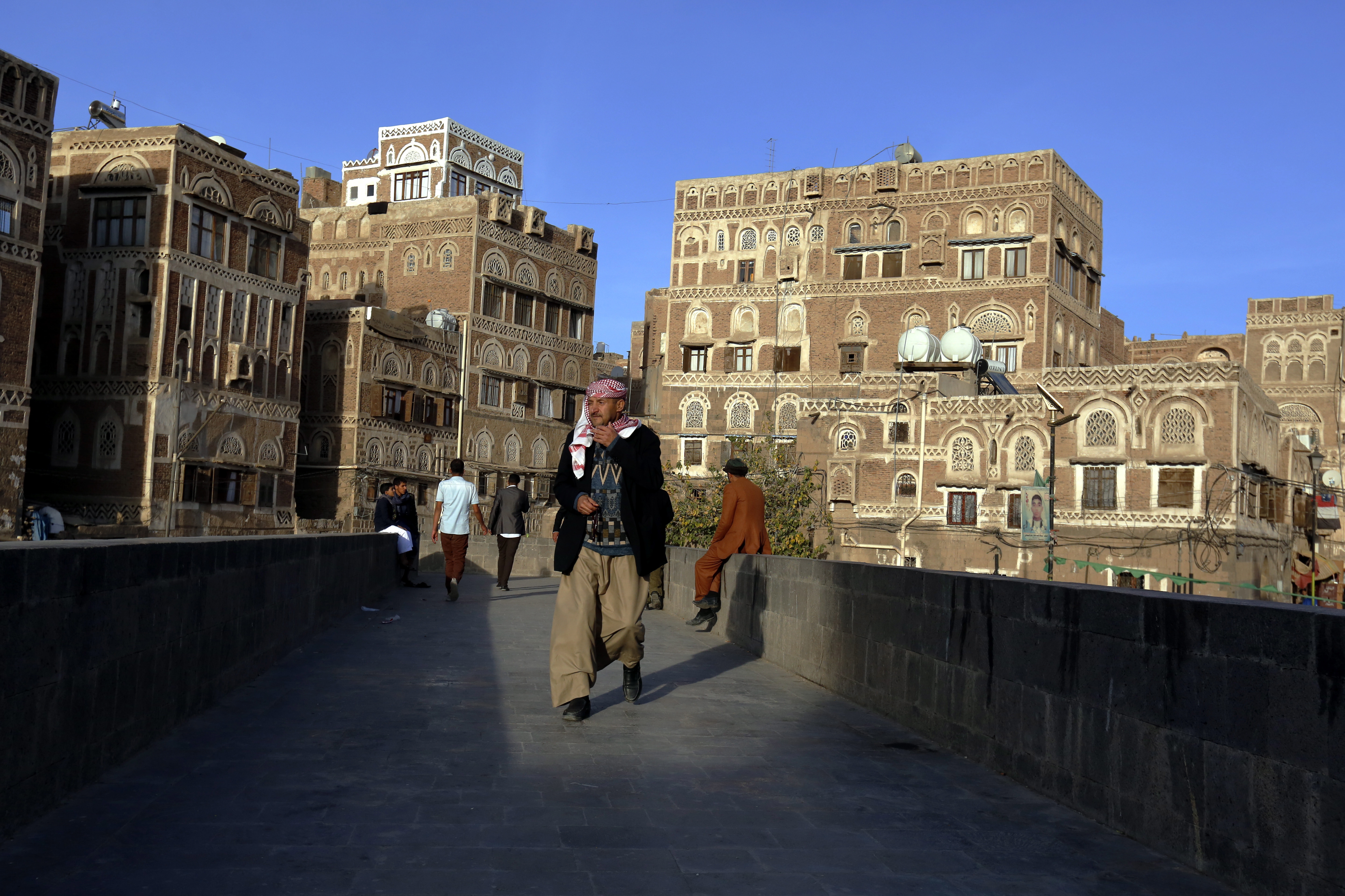 epa07253463 Yemenis walk past historic buildings in the old quarter of Sana'a, Yemen, 29 December 2018. According to reports, Yemeni Houthi rebels have begun to pull out their forces from the strategic port city of Hodeidah under the recent ceasefire agreement reached between the warring parties.  EPA/YAHYA ARHAB