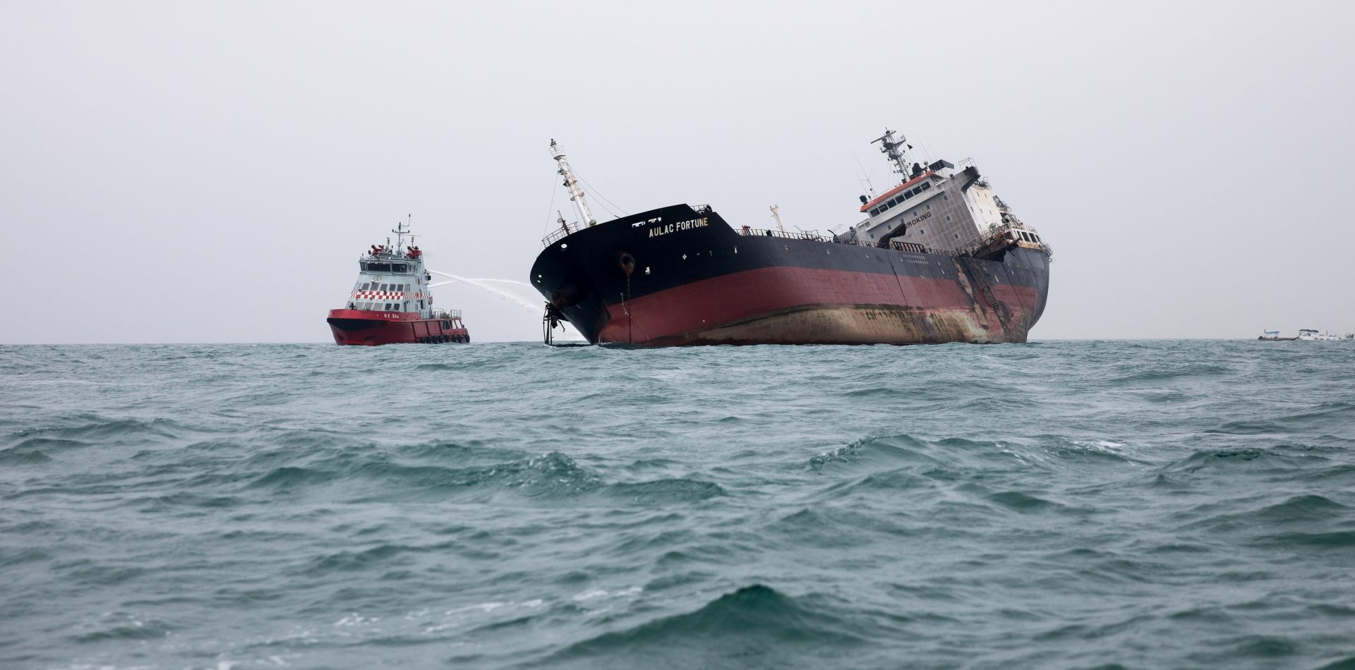 epa07268901 A firefighting ship sprays a vessel, an oil and chemical tanker named Aulac Fortune, off shore from Lamma Island in Hong Kong, China, 08 January 2019. According to media reports, at least one person is dead and two others are missing after the Aulac Fortune caught fire off the coast of Lamma Island. Emergency personnel rescued 23 other sailors who had either fallen or jumped into the sea to escape the blaze.  EPA/JEROME FAVRE