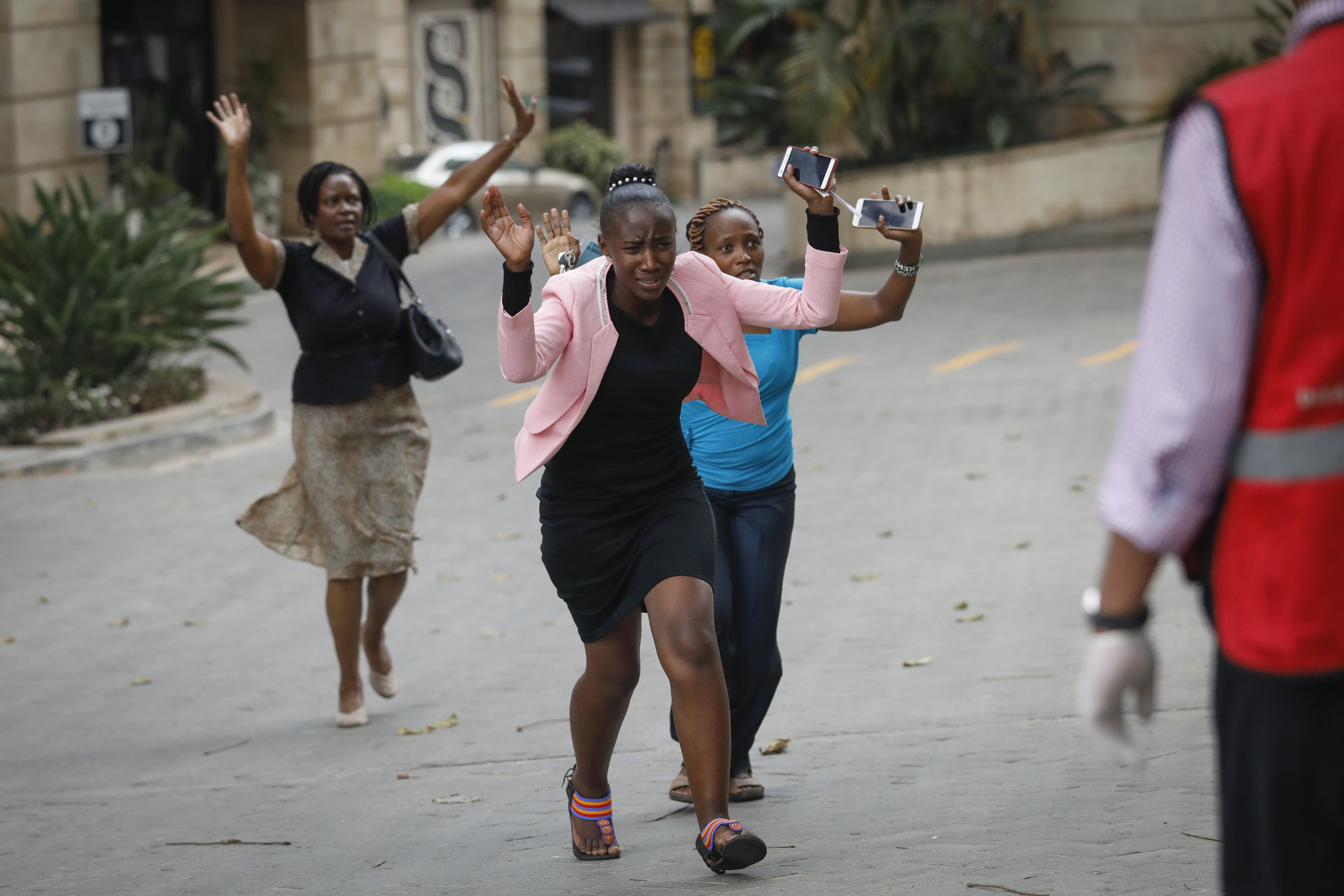 epa07287256 Women raise their hands as they make a run for the rescue workers, during an ongoing gunfire and explosions in Nairobi, Kenya, 15 January 2019. According to reports, a large explosion and sustained gunfire sent workers fleeing for their lives at an upscale hotel and office complex in the Kenyan capital of Nairobi.  EPA/DAI KUROKAWA
