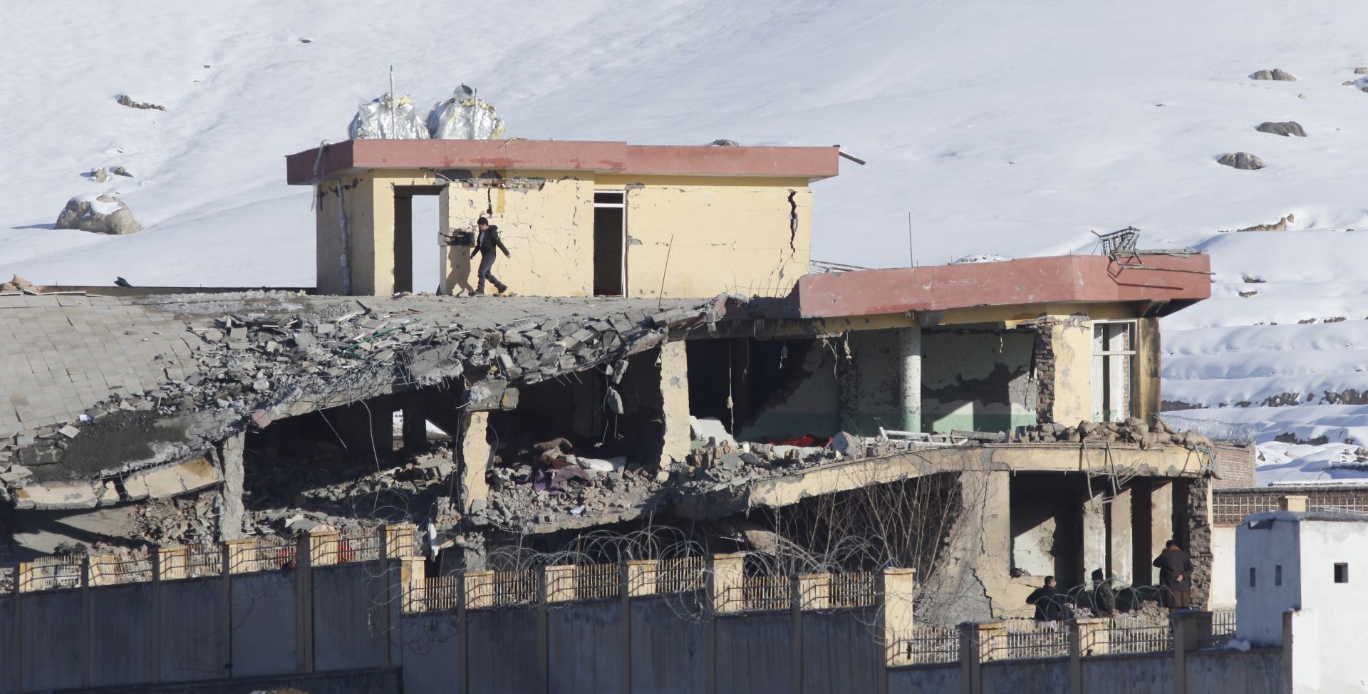 epa07306269 An Afghan security officer walks on the top of a collapsed building of Afghanistan's intelligence office in Wardak, Afghanistan, 21 January 2019. A Taliban Humvee tank full of explosive materials targeted the building with following attack of several other insurgents early in the morning.  According to the Afghan officials at least 18 officers were killed and 50 others wounded.  EPA/JAWAD JALALI