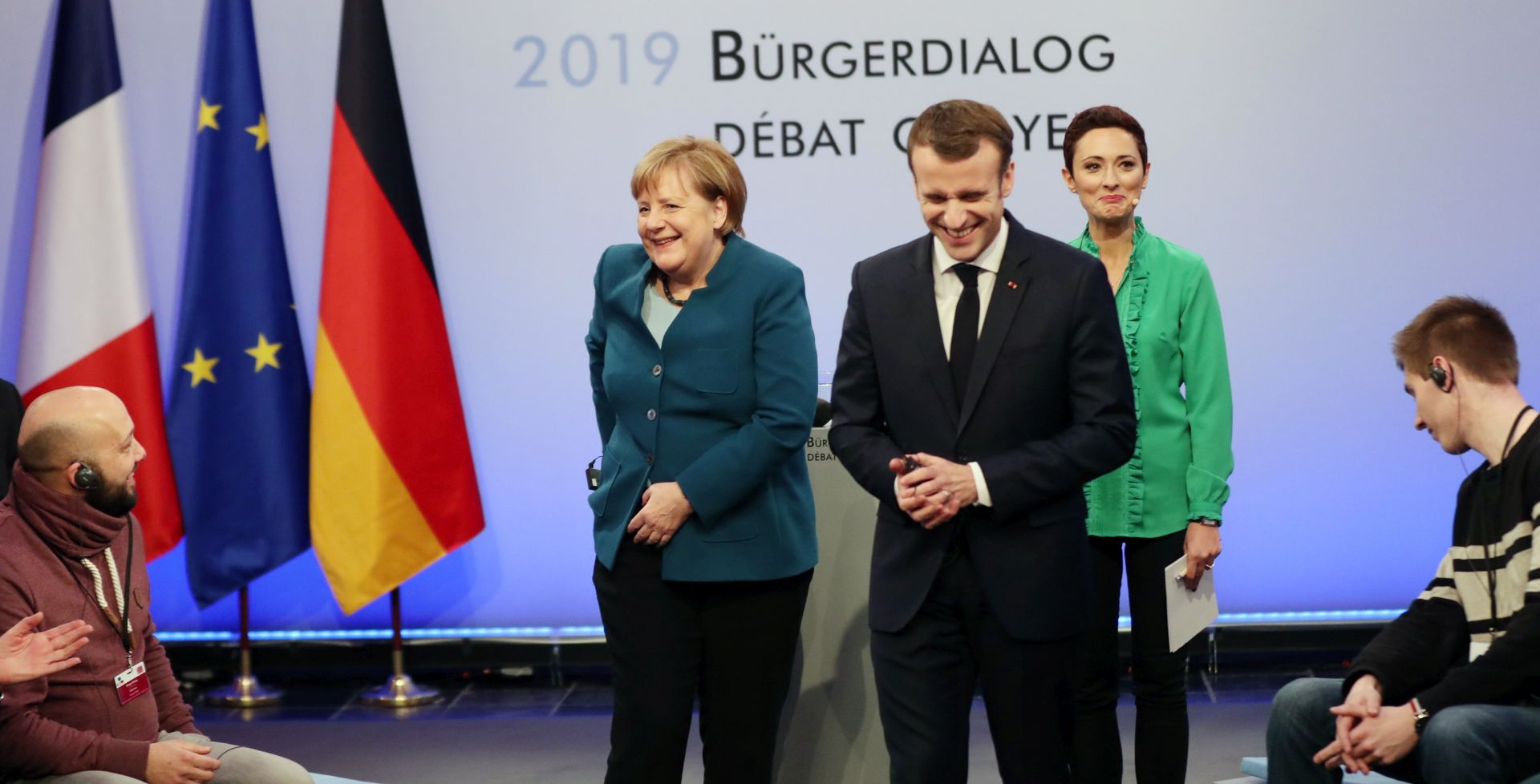 epa07308936 German Chancellor Angela Merkel (C-L) and French President Emmanuel Macron (C-R) react during a civil dialogue at the signing of a new France-German friendship treaty in Aachen, Germany, 22 January 2019. President Macron and Chancellor Merkel sign a new friendship treaty, intended to supplement the 1963 Elysee Treaty, pledging to provide deeper economic and defense ties and commitment to the EU.  EPA/FRIEDEMANN VOGEL