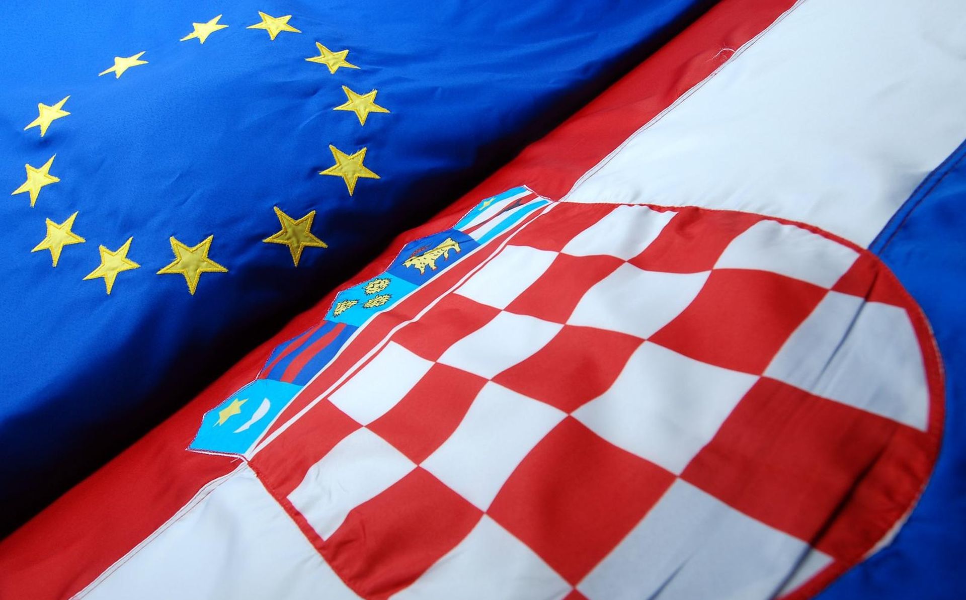 23.06.2013., Zagreb, - Zastave Europske unije i Republike Hrvatske. Dvanaest zlatnih zvjezdica slozenih u krugu na plavoj podlozi na zastavi Europske unije oznacava ideale zajednistva, solidarnosti i sklada medju europskim narodima. Povijest zastave EU seze u 1955. godinu kada je Vijece Europe prihvatilo njezin dizajn i pocelo ga koristiti, a sljedecih godina Vijece Europe poticalo je i druge europske institucije na prihvacanje takve zastave. Godine 1983. zastavu je potvrdio i Europski parlament, a dvije godine poslije kao sluzbeni simbol potvrdili su je svi vodje EU koja se tada jos zvala Europska zajednica. Prvo postavljanje zastava EU pocelo je 2004. godine, sto je tri mjeseca nakon sto je EU Hrvatskoj dodijelio status kandidata za punopravno clanstvo. 
Photo: Luka Stanzl/PIXSELL