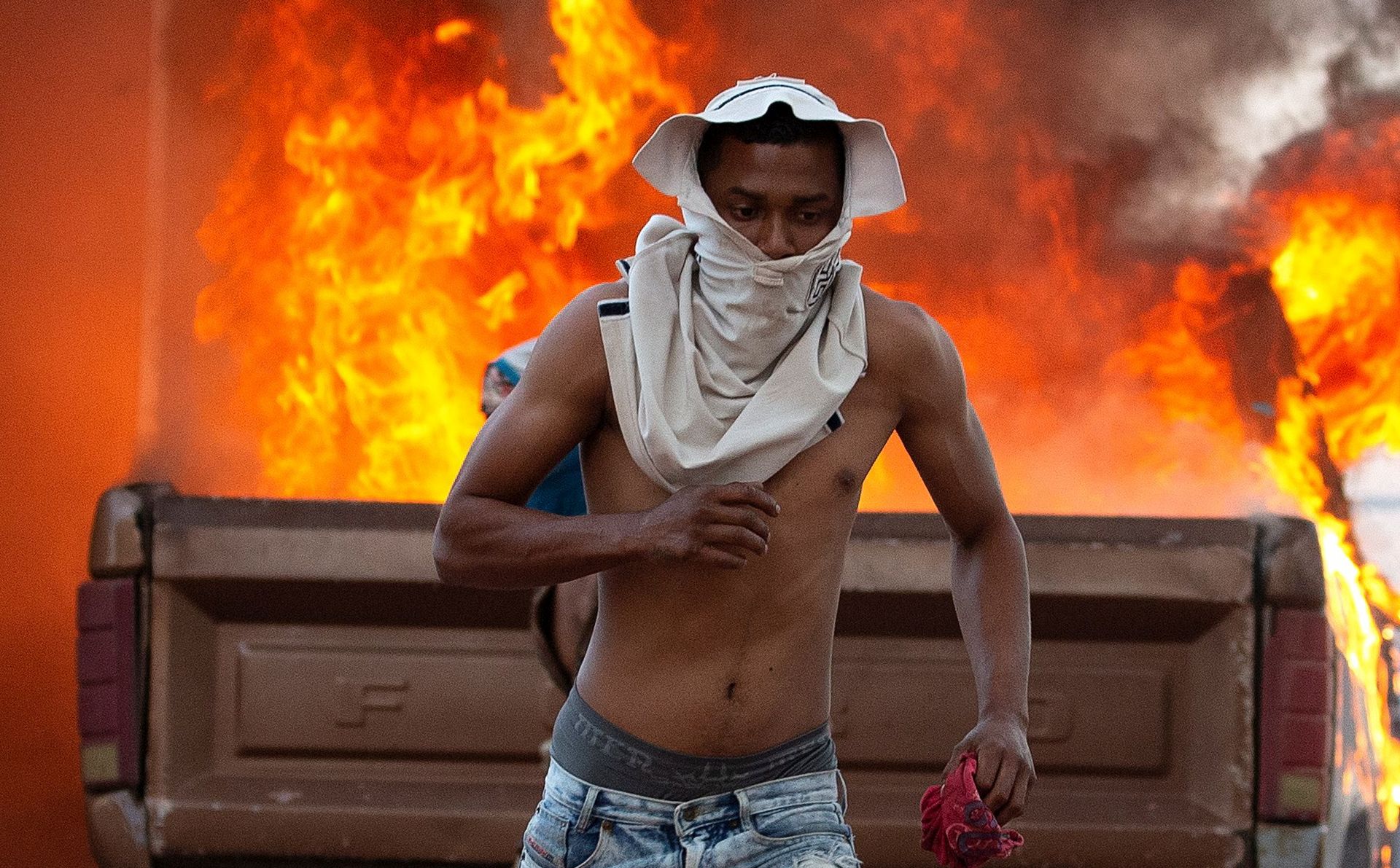 epaselect epa07391507 A person runs during clashes between opponents of Venezuelan President Nicolas Maduro and members of the Bolivarian National Guard of Venezuela at the border crossing located in the town of Pacaraima, on the border between the two countries, closed since Thursday by order of the Government of Nicolas Maduro, 23 February 2019.  EPA/Joédson Alves