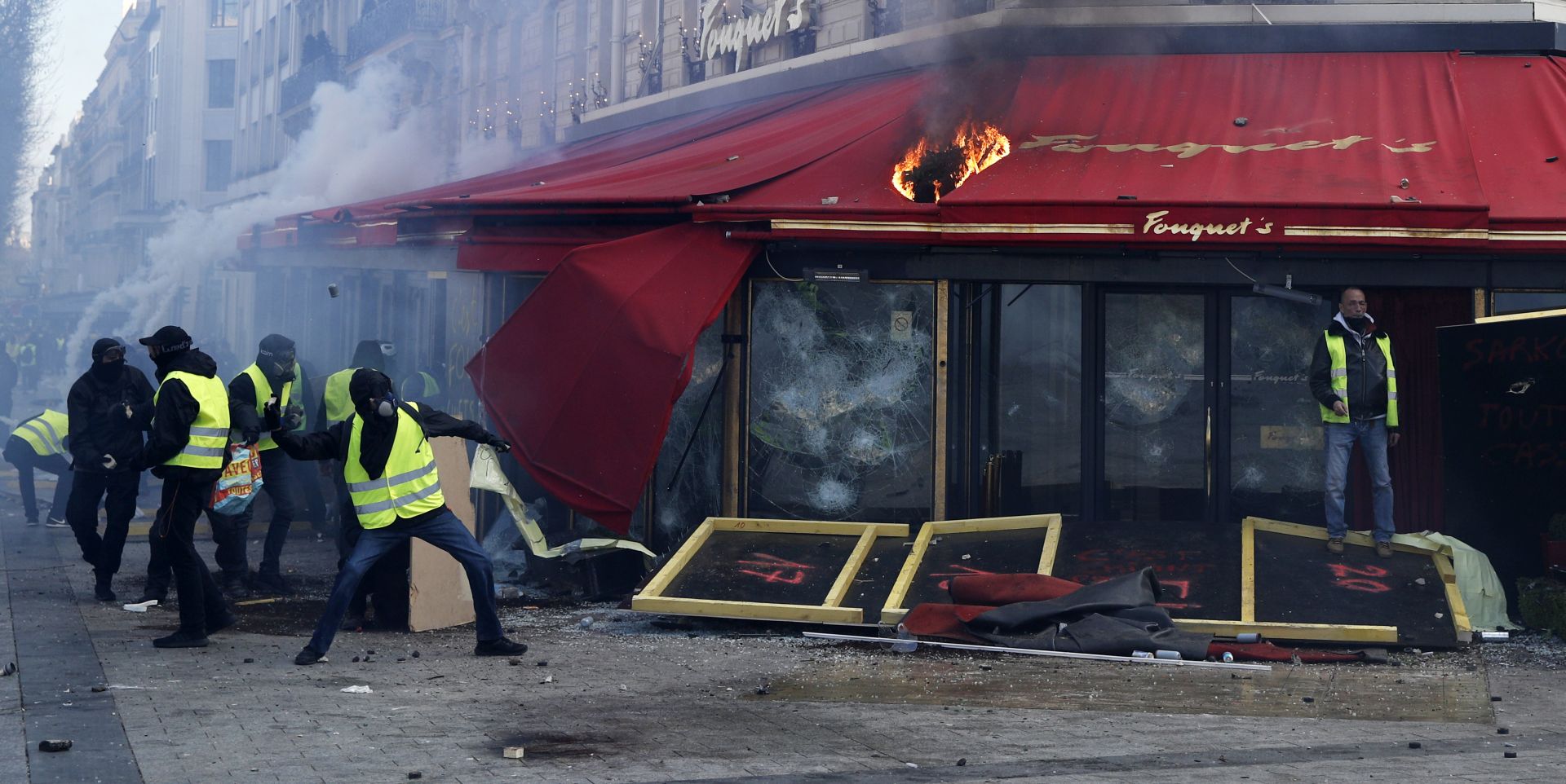 epa07442862 Yellow Vests protesters clash with rior police in front of the Fouquet's restaurant on fire during the 'Act XVIII' demonstration (the 18th consecutive national protest on a Saturday) in Paris, France, 16 March 2019. The so-called 'gilets jaunes' (yellow vests) is a grassroots protest movement with supporters from a wide span of the political spectrum, that originally started with protest across the nation in late 2018 against high fuel prices. The movement in the meantime also protests the French government's tax reforms, the increasing costs of living and some even call for the resignation of French President Emmanuel Macron.  EPA/YOAN VALAT