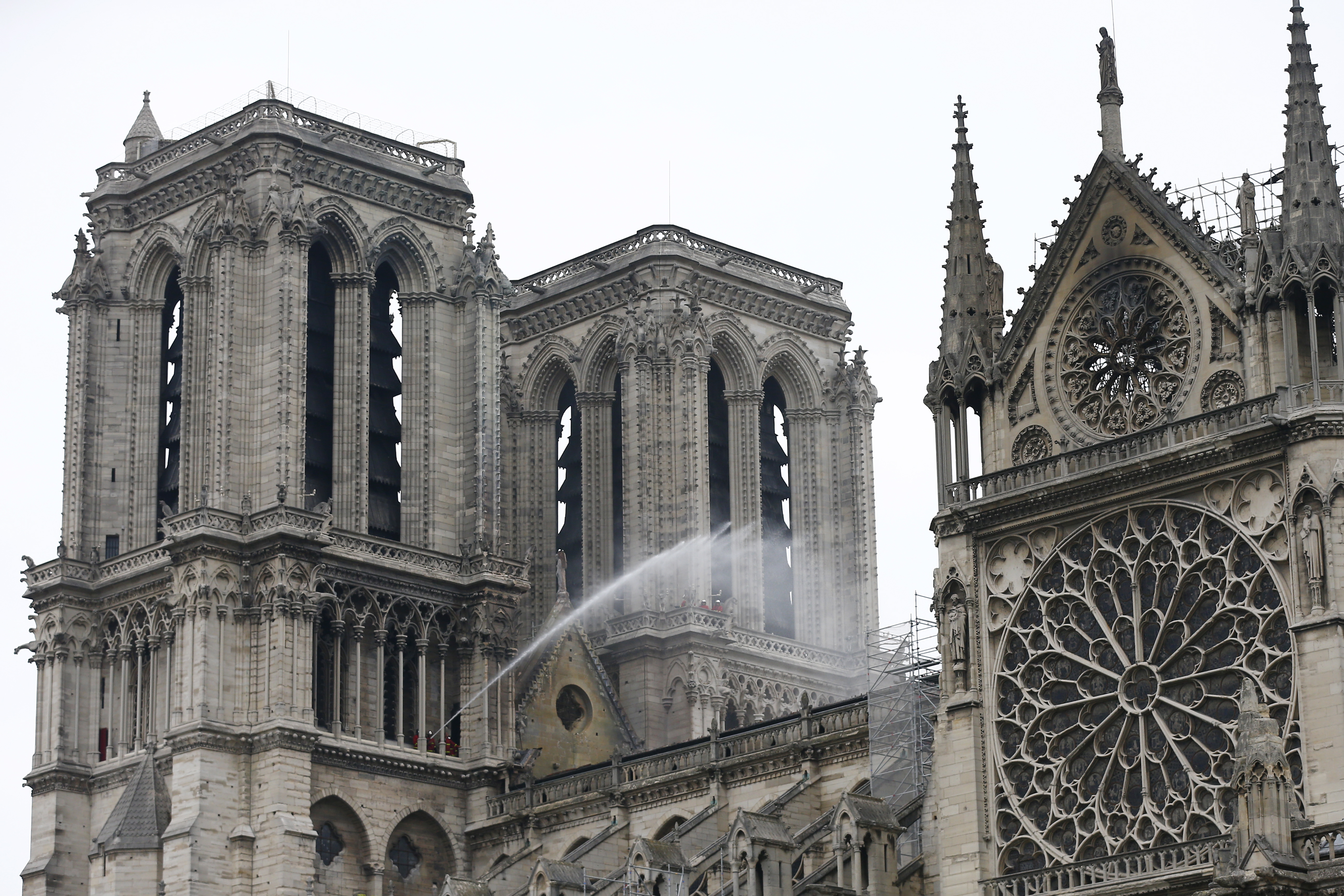 epa07510403 Fire fighters continue to spray water after a massive fire destroyed the roof of the Notre-Dame Cathedral in Paris, France, 16 April 2019. A fire started in the late afternoon 15 April in one of the most visited monuments of the French capital.  EPA/IAN LANGSDON