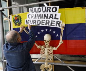 epa07538871 A supporter of Venezuela opposition leader Juan Guaido hangs a sign during a rally in front of the now-shuttered Venezuelan consulate in New York, New York, USA, 30 April 2019.The struggle for power in Venezuela between Guaido, who declared himself the interim president of Venezuela earlier this year, and President Nicolas Maduro escalated this week and there is speculation that the country's military may been shifting its allegiance to Guaido's opposition party.  EPA/JUSTIN LANE