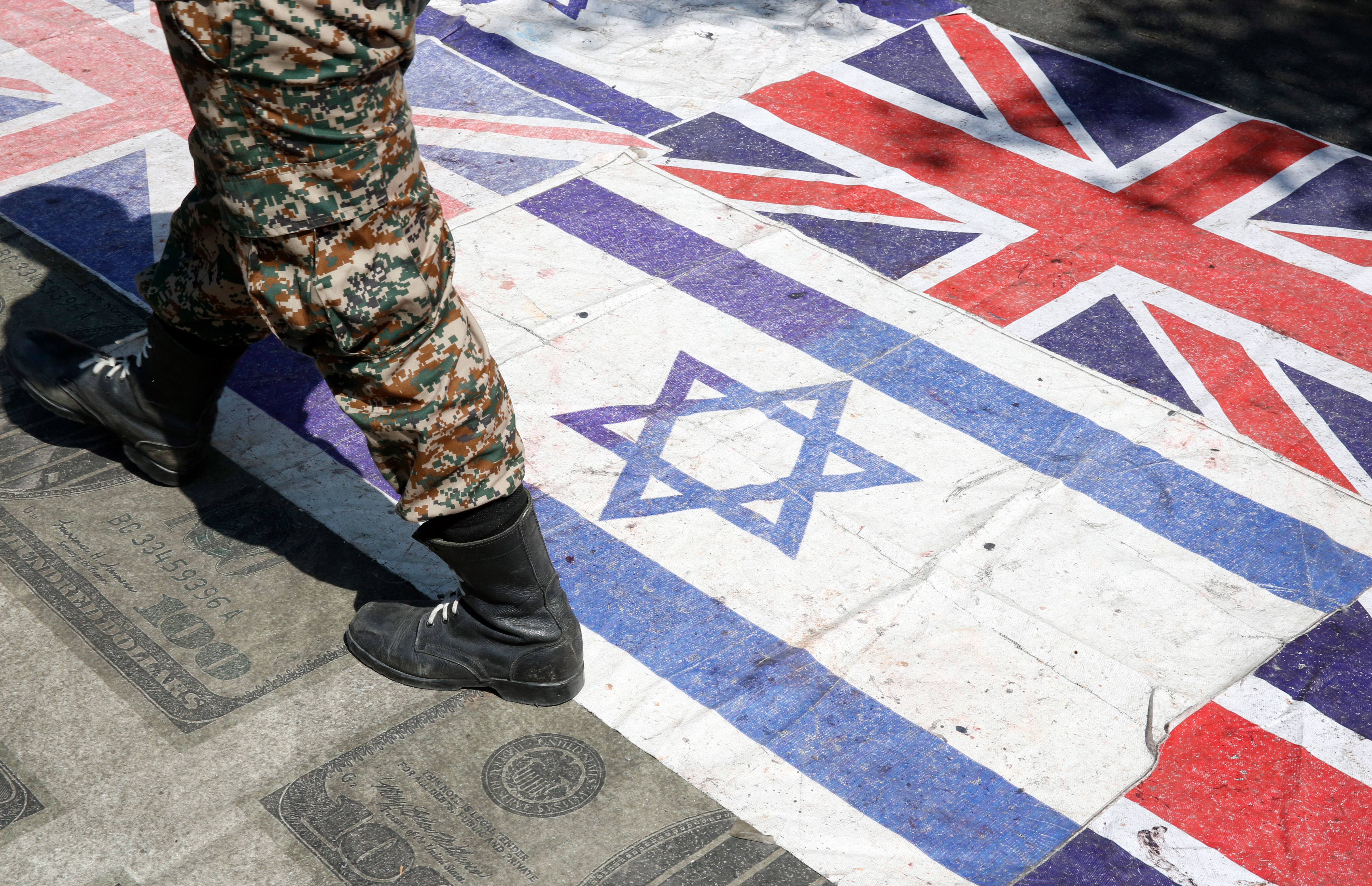 epa07614657 An Iranian soldier walks on Britain and Israel flags during an anti-Israel rally mark Al Quds Day (Jerusalem Day), in support of Palestinian resistance against on the Israeli occupation, in Tehran, Iran, 31 May 2019. Quds Day was started by the late Ayatollah Khomeini, founder of the Islamic Iranian republic, who called on the world's Muslims to show solidarity with Palestinians on the last Friday of the fasting month of Ramadan.  EPA/ABEDIN TAHERKENAREH