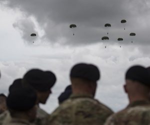 epa07627006 US Airborne soldiers look on as C-47 Dakota airplanes drop parachutists in WW2 attire near the Normandy coast ahead of the 75th D-Day anniversary, in Carentan,  France, 05 June 2019. World leaders are to attend memorial events in Normandy, France on 06 June 2019 to mark the 75th anniversary of the D-Day landings, which marked the beginning of the end of World War II in Europe.  EPA/IAN LANGSDON