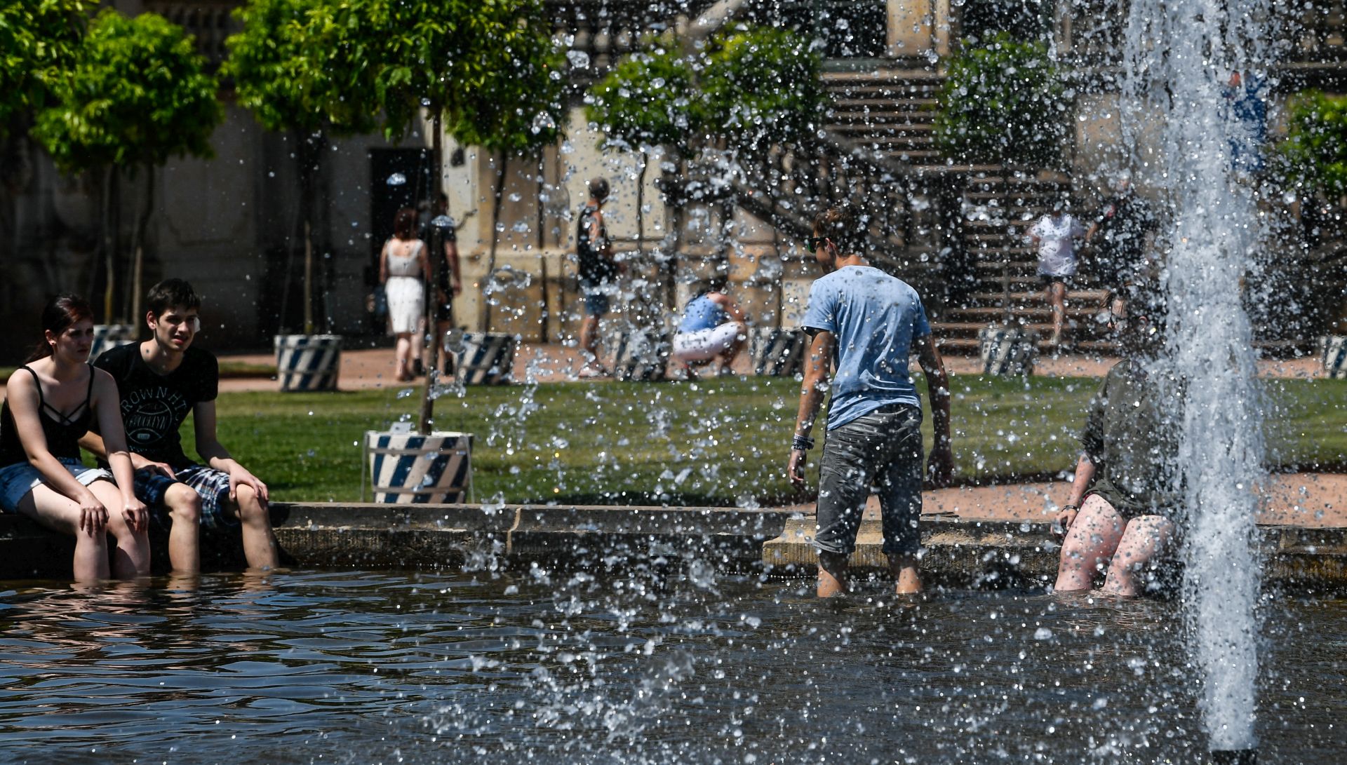 epa07674698 People cool off at a fountain at the yard of the Zwinger palace in Dresden, Germany, 26 June 2019. Temperatures registered 38 degrees Celsius in Eastern Germany.  EPA/FILIP SINGER