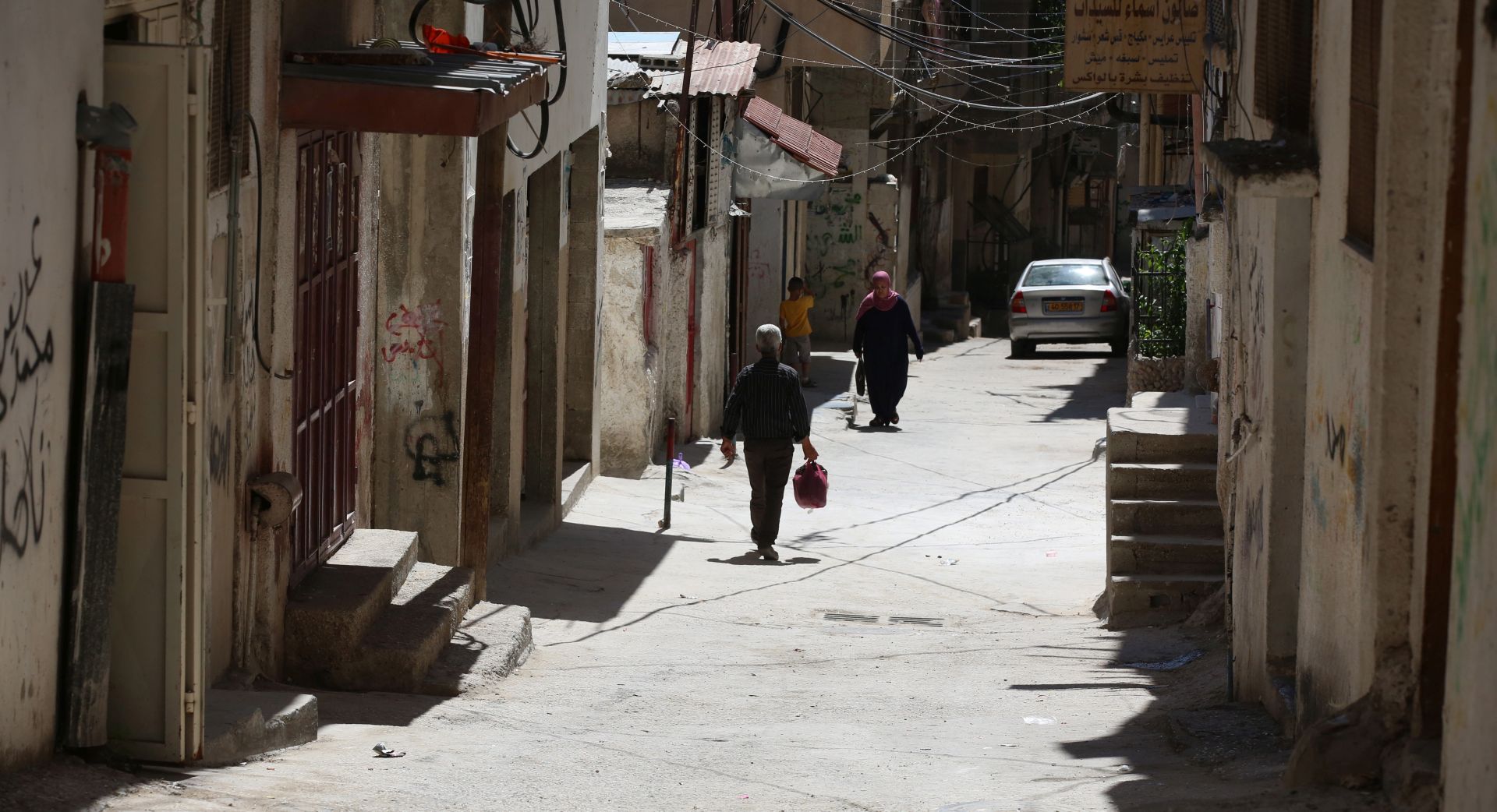 epa07673966 Palestinians walk on a street at the Balata refugee camp near the West Bank city of Nablus, 26 July 2019.  EPA/ALAA BADARNEH