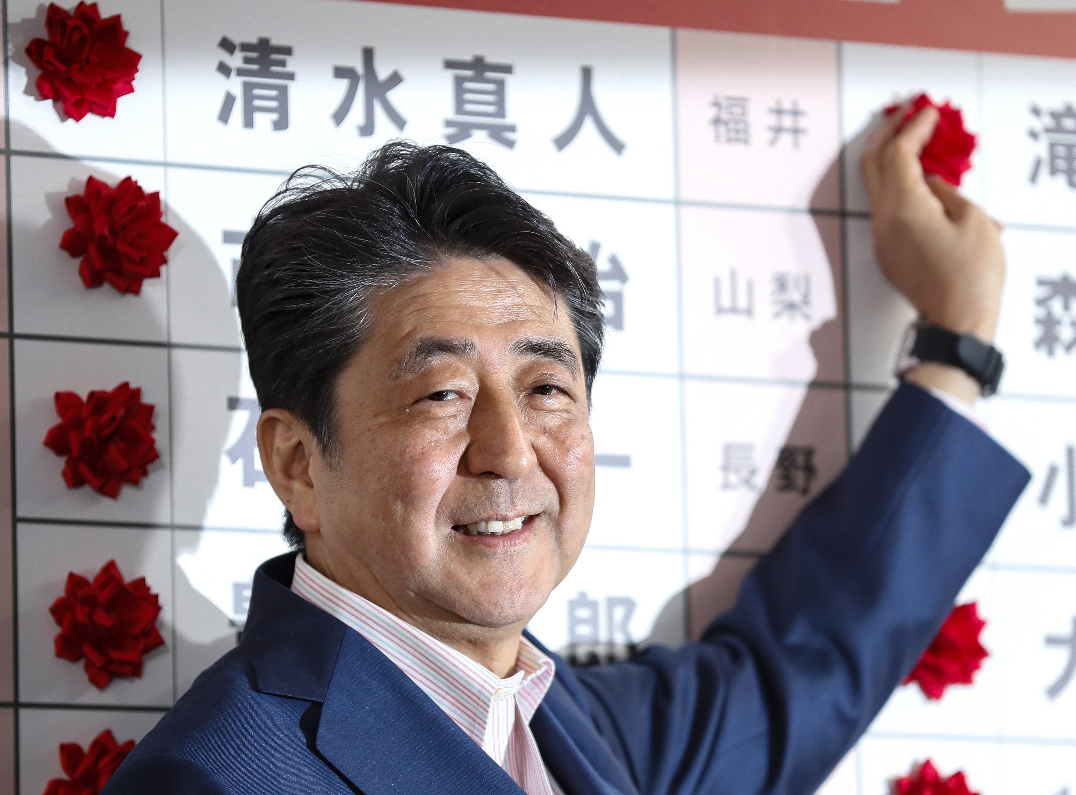epa07731429 Japanese Prime Minister and the ruling Liberal Democratic Party (LDP) President, Shinzo Abe, puts red rose marks on the names of the party's victorious candidates in the Upper House election, at the LDP headquarters in Tokyo, Japan, 21 July 2019. Exit polls suggest that Abe's LDP and its junior coalition partner, Komeito, will win over half of the seats being contested for the Upper House.  EPA/KIMIMASA MAYAMA
