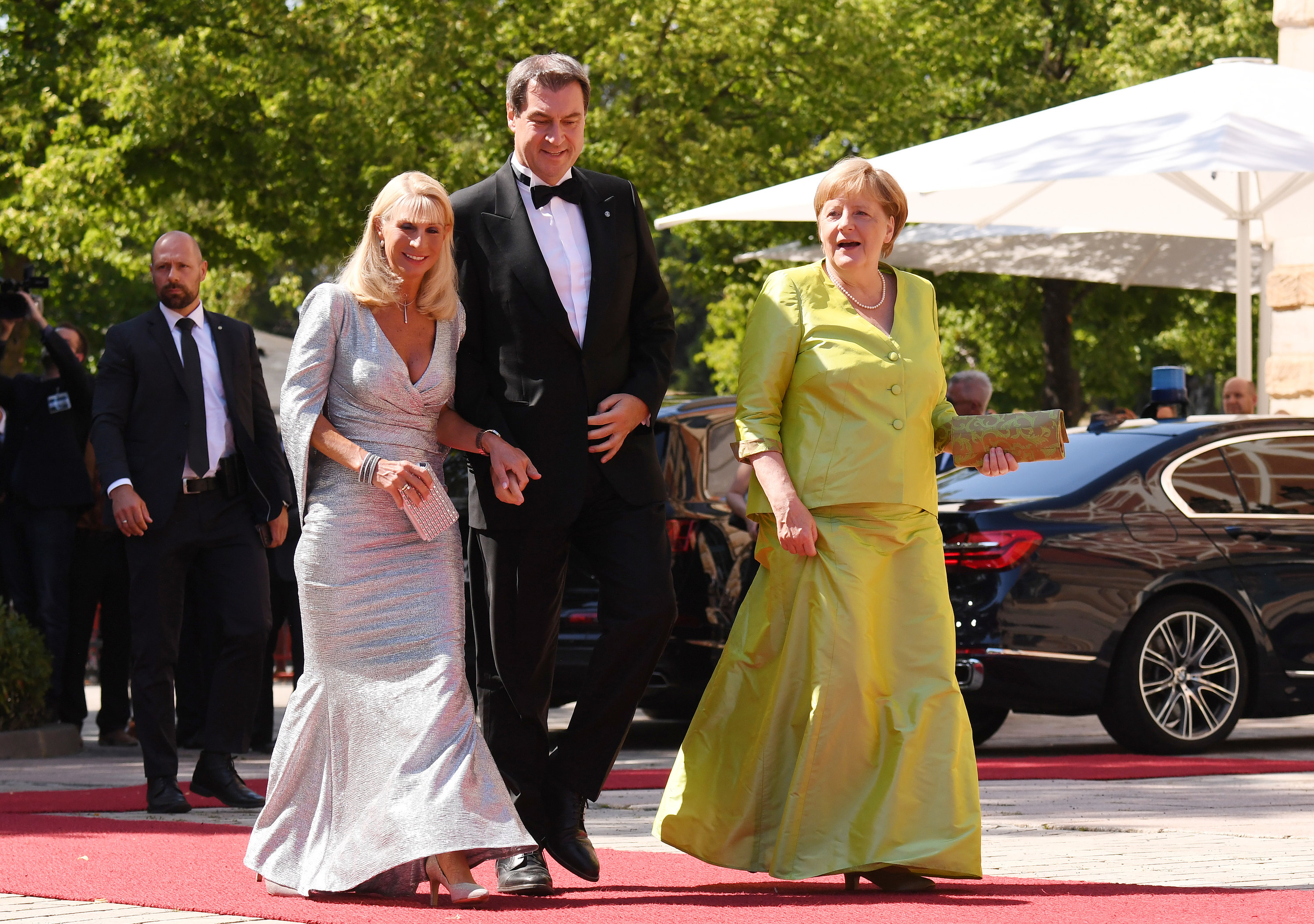 25 July 2019, Bavaria, Bayreuth: German Chancellor Angela Merkel (R) arrives together with Minister President of Bavaria Markus Soeder (C) and his wife Karin Baumueller-Soeder at the beginning of the 2019 Bayreuth Festival 2019, also referred to as the Richard Wagner Festival. Photo: Tobias Hase/dpa