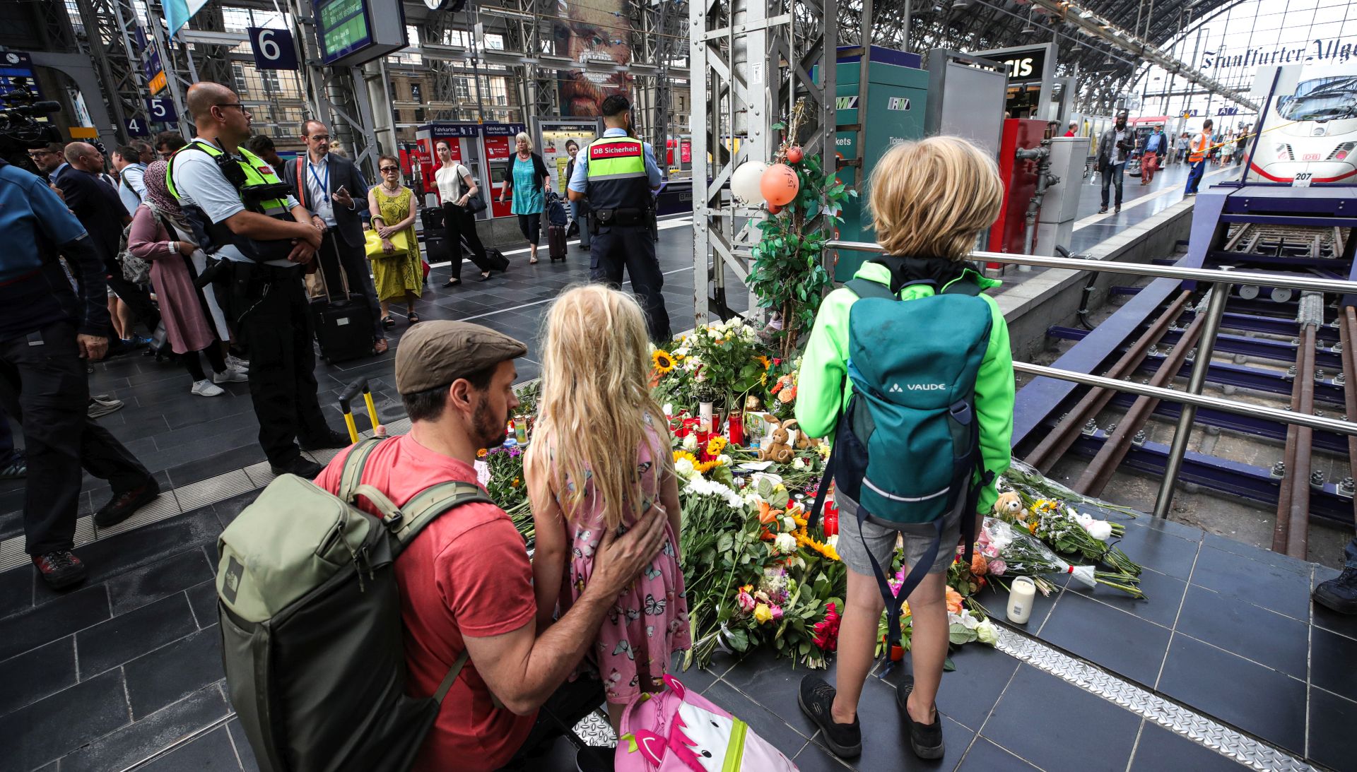 epa07748273 A father with his kids put flowers and candles to pay tribute at the main train station in Frankfurt am Main, Germany, 30 July 2019, one day after an eight-year-old boy died after being pushed onto the rail tracks in front of an oncoming train. The boy's mother was also pushed onto the tracks but was able to save herself. One man has been arrested in connection with the attack.  EPA/ARMANDO BABANI