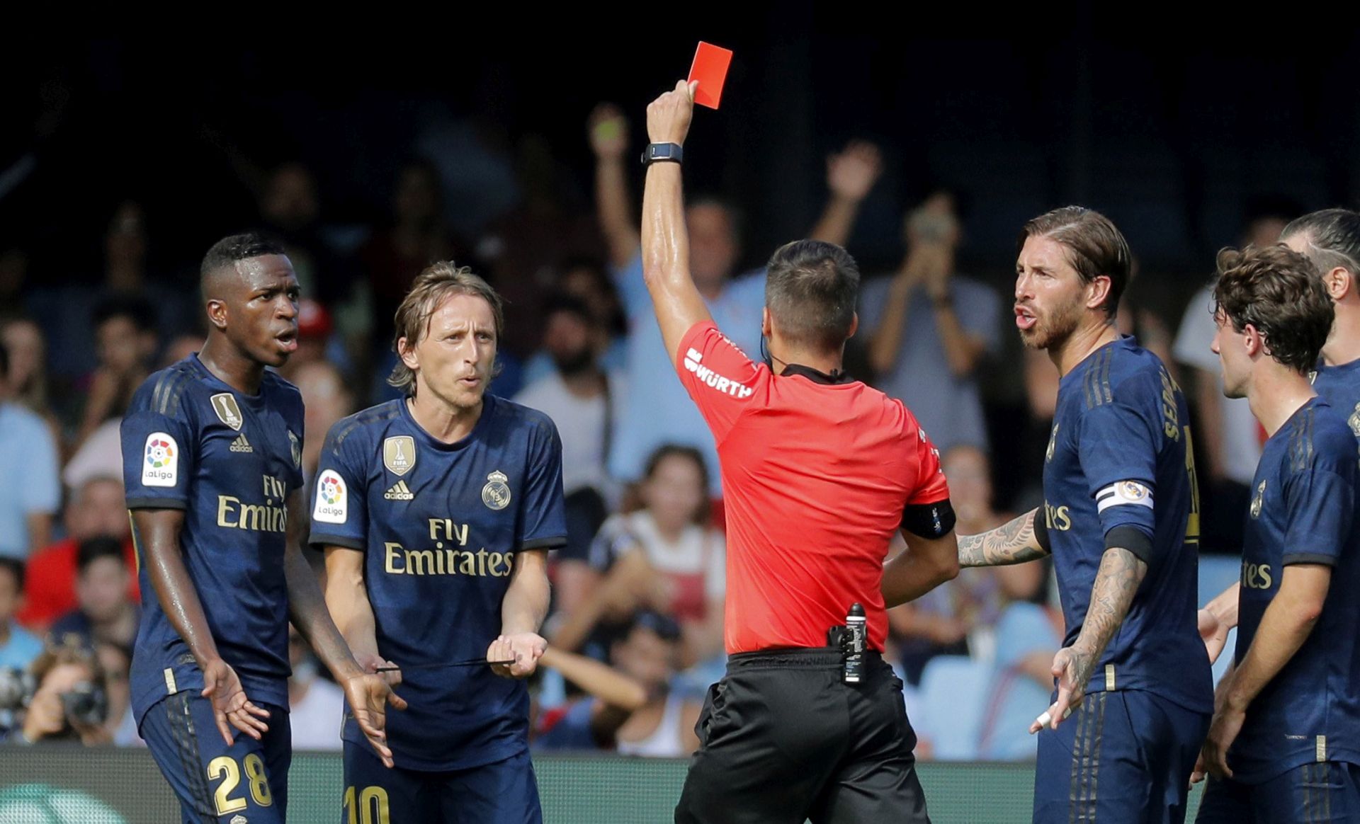 epa07778098 Referee Javier Estrada (C) raises a red car against Real Madrid's Croatian midfielder Luka Modric, next to Vinicius Jr. (L) and Sergio Ramos (2-R), after an action against Celta Vigo's Denis Suarez (unseen) during their LaLiga game at Balaidos Stadium, in Vigo, northwestern Spain, 17 August 2019.  EPA/Lavandeira Jr