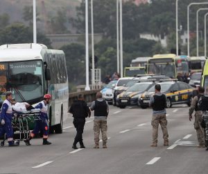 epa07782076 A woman is taken on a stretcher after she passed out moments after she was released from a bus by a hijacker in the Rio-Niteroi bridge in Rio de Janeiro, Brazil, 20 August 2019. A masked armed man hijacked a bus and keeps passengers and driver as hostages while he threatens to burn the vehicle with petrol.  EPA/ANTONIO LACERDA