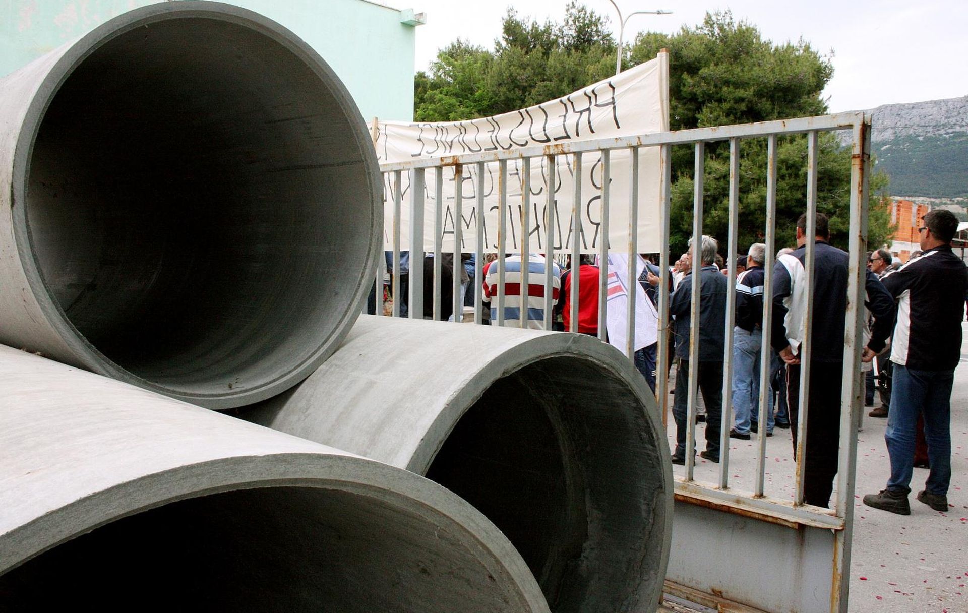 18.05.2010.,Vranjic, Hrvatska - Radnioci Salonita ponovno prosvjedovali ispred tvornice u Vranjicu. Radnik se simbolicno vezao, a zatim su stavili azbestne cjevi na ulaz
Photo: Ivana Ivanovic/PIXSELL