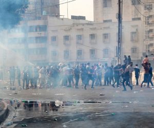epa07886317 Iraqi protesters run for cover amid tear gas fired by policemen during a demonstration at al-Tahrir square, central Baghdad, Iraq, 01 October 2019. According to media reports, dozens of protesters were injured in the clashes that occurred as thousands of Iraqis were protesting over unemployment, the rising cost of living and lack of services in Baghdad. The Iraqi government had deployed a significant amount of military and police forces around the fortified green zone which is the headquarter of the Iraqi government in Baghdad.  EPA/AHMED JALIL