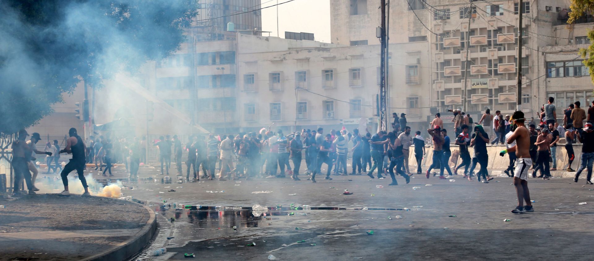 epa07886317 Iraqi protesters run for cover amid tear gas fired by policemen during a demonstration at al-Tahrir square, central Baghdad, Iraq, 01 October 2019. According to media reports, dozens of protesters were injured in the clashes that occurred as thousands of Iraqis were protesting over unemployment, the rising cost of living and lack of services in Baghdad. The Iraqi government had deployed a significant amount of military and police forces around the fortified green zone which is the headquarter of the Iraqi government in Baghdad.  EPA/AHMED JALIL