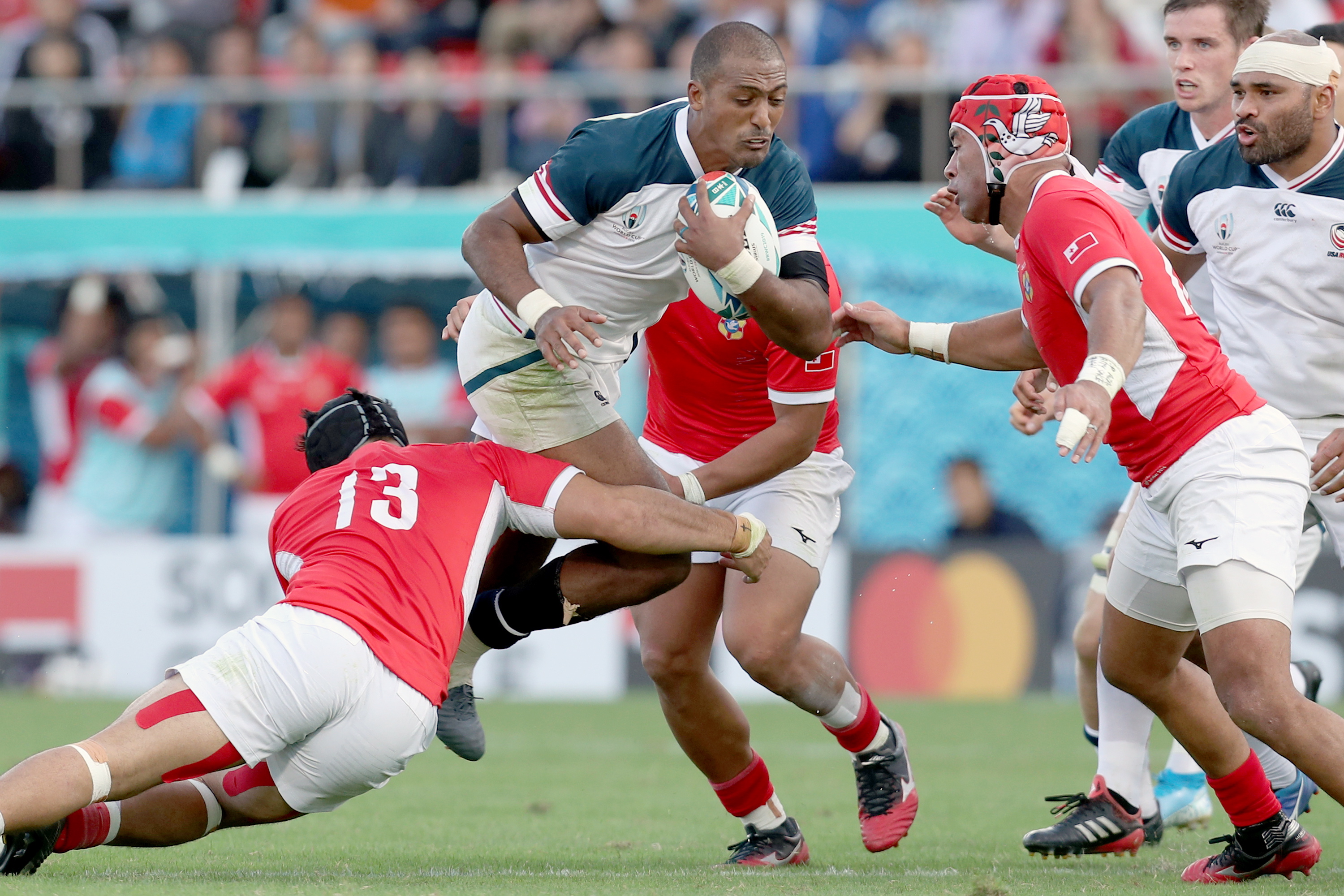 epa07916995 Marcel Brache of the USA (C) in action with the ball against Tonga players during the Rugby World Cup match between USA and Tonga at Hanzono Stadium in Higashiosaka, Japan, 13 October 2019.  EPA/BUDDHIKA WEERASINGHE EDITORIAL USE ONLY/ NO COMMERCIAL SALES / NOT USED IN ASSOCATION WITH ANY COMMERCIAL ENTITY