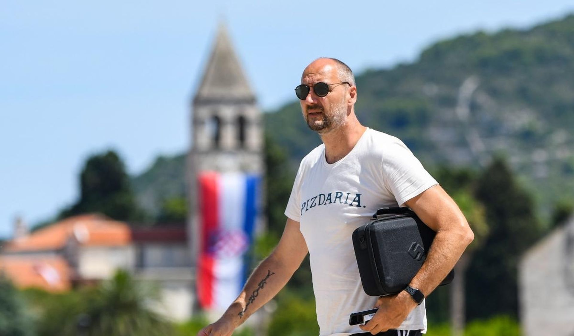 05.08.2019. Vis - Dino Radja u drustvu prijatelja prosetao viskom rivom noseci majicu na natpisom "pizdarija".  Photo: Josip Regovic/PIXSELL